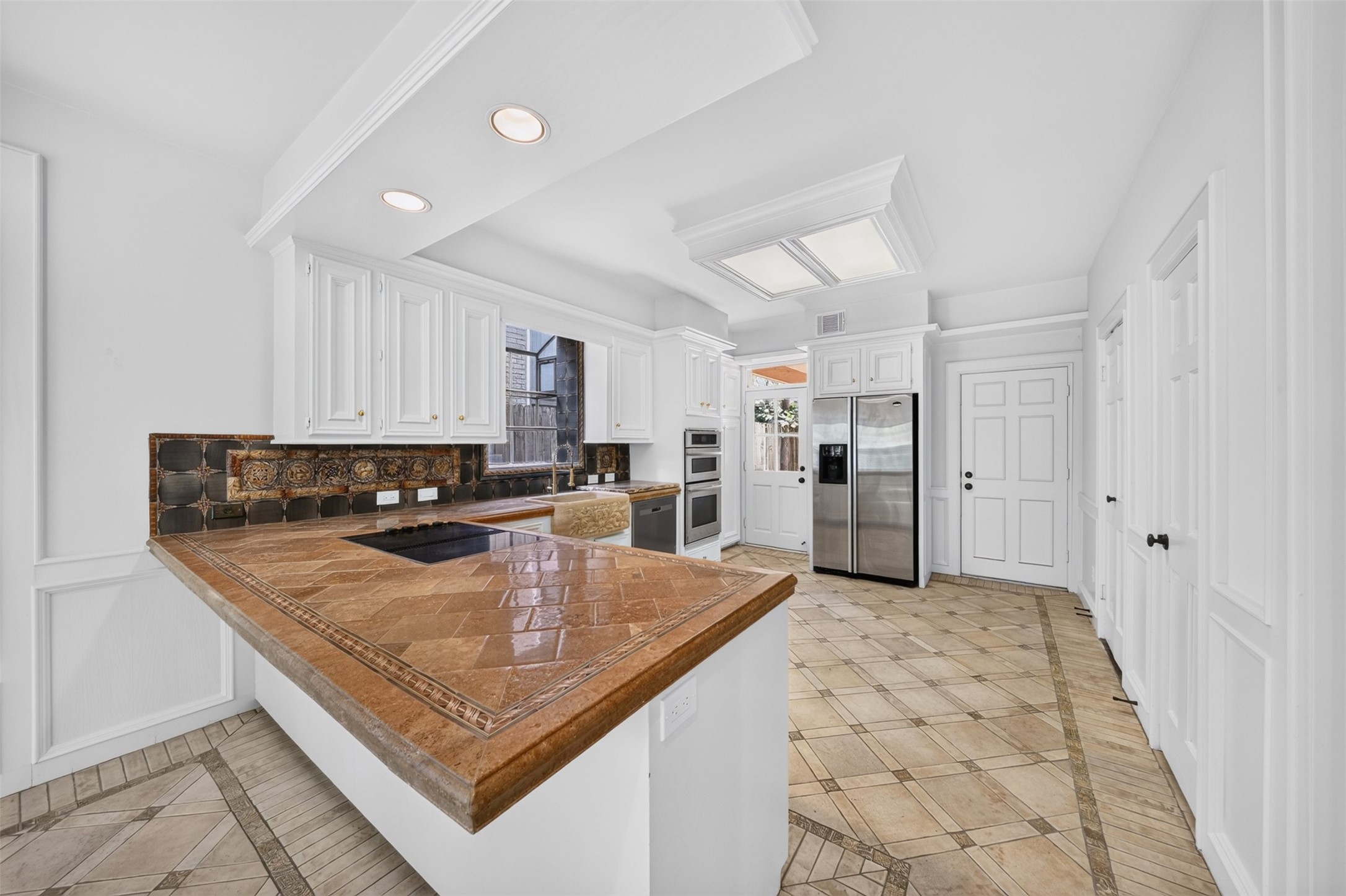 Wraparound kitchen counter with an inset cooktop and white cabinetry.