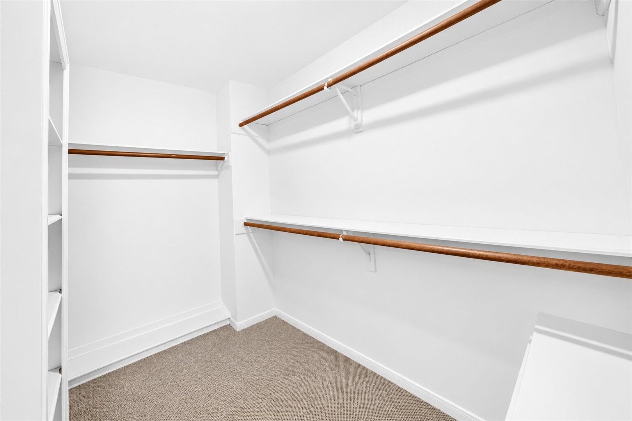 Walk-in closet with shelving and two levels of hanging rails along one wall.
