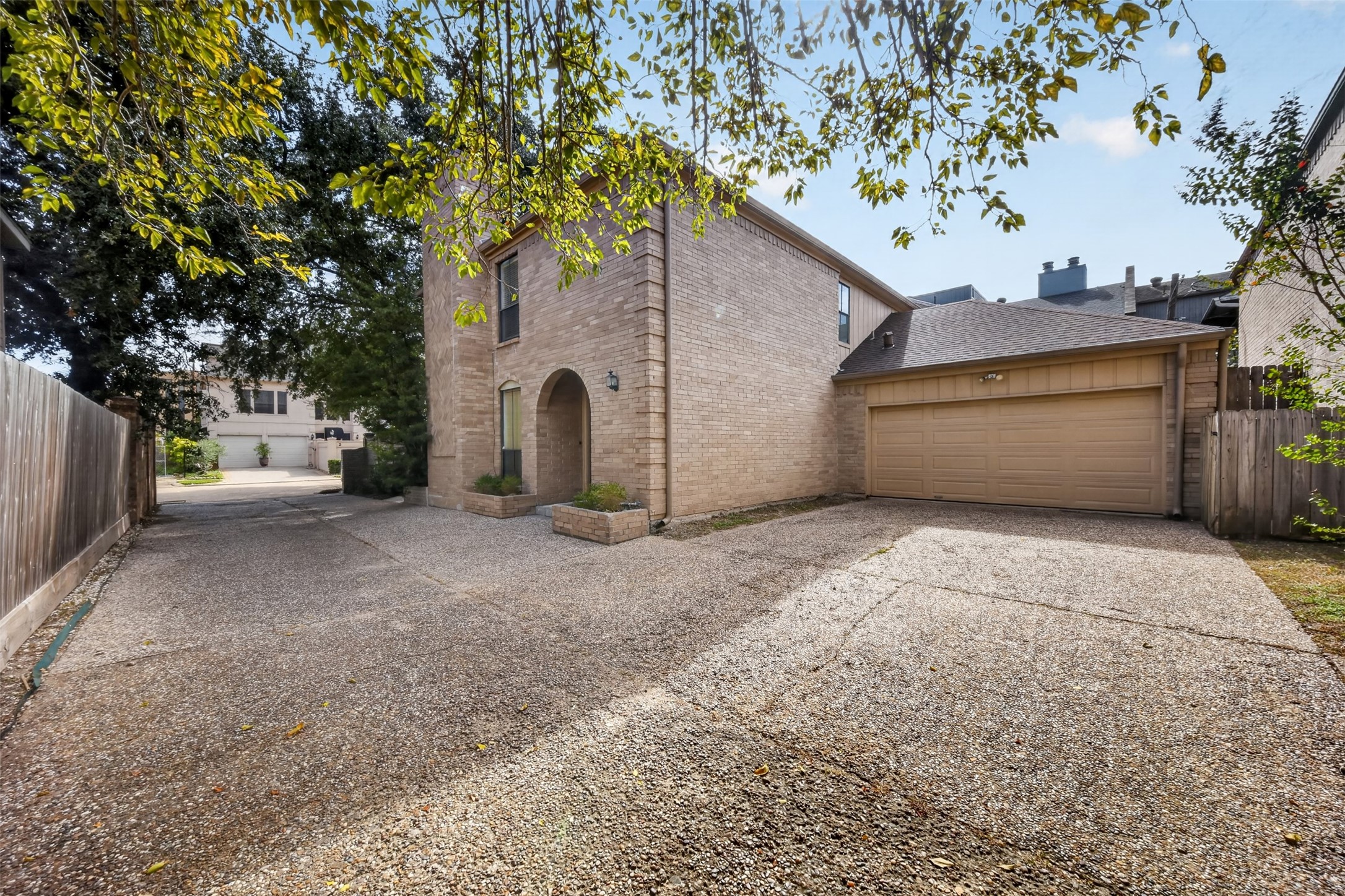Alternate exterior view shows the arched entry, garage door and paved approach.