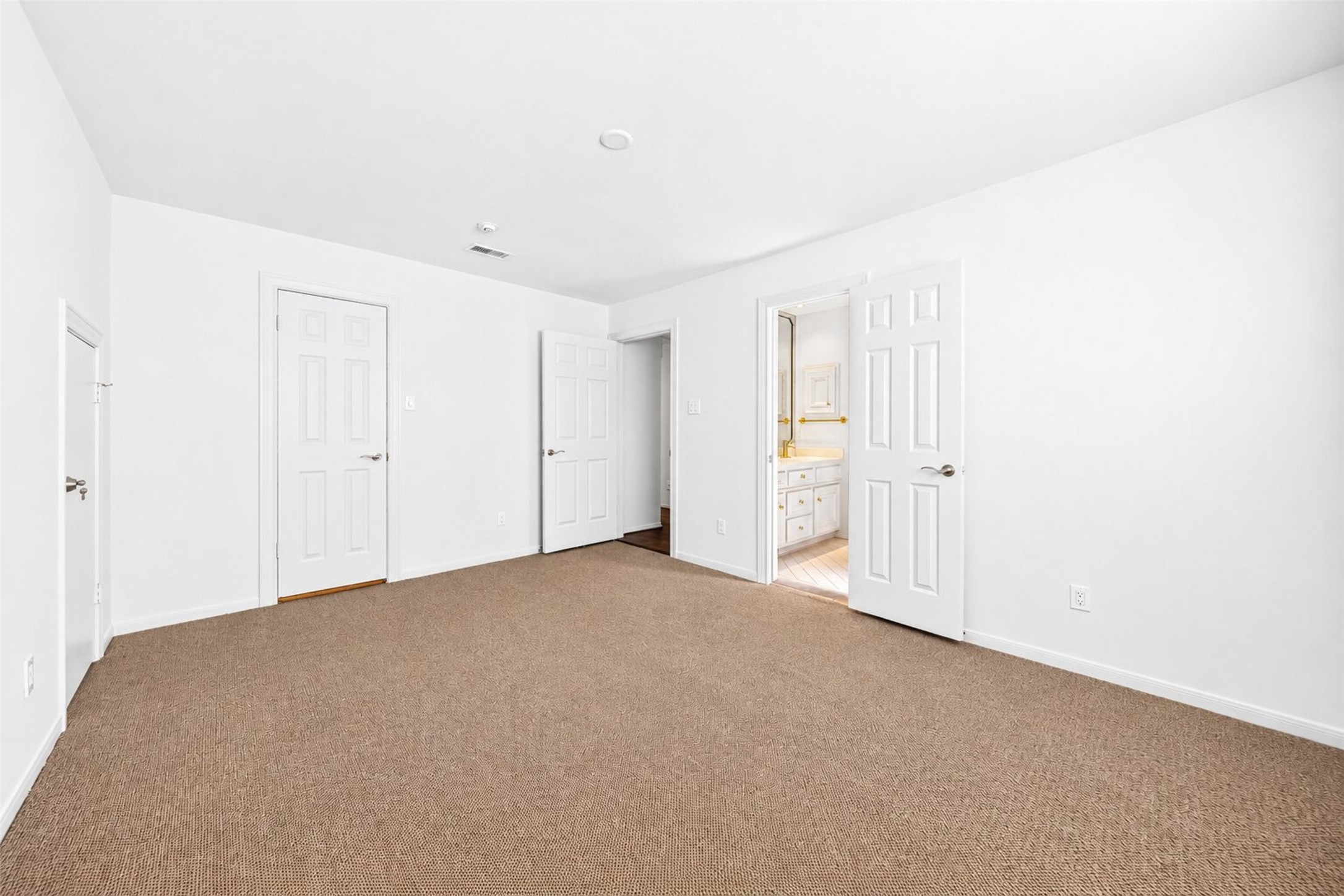 Alternate bedroom view shows closet and hall doors beside the adjoining vanity area.
