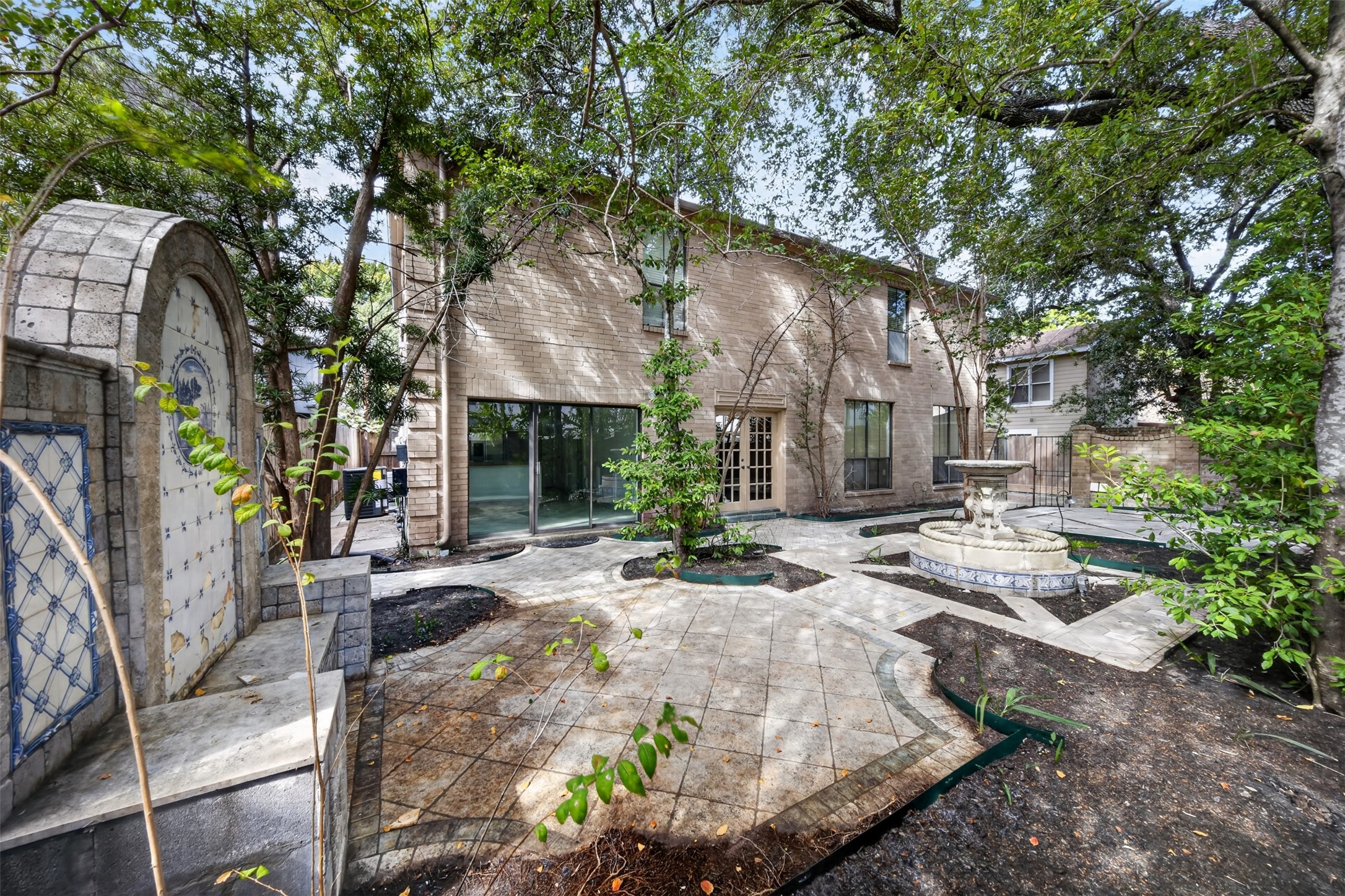 Reverse courtyard view captures the fountain, curved planting beds and multiple glass doors.
