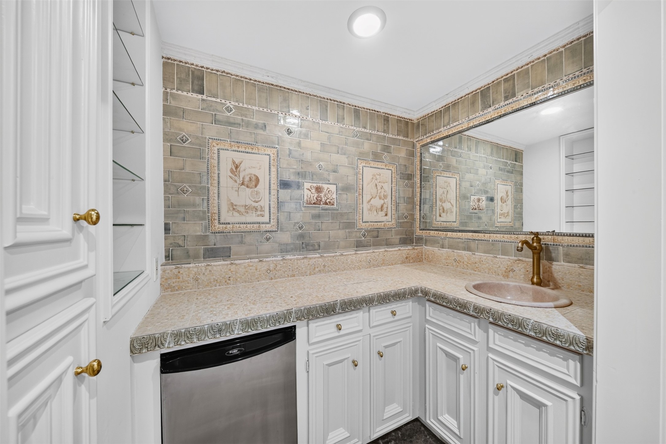 Wet bar with white cabinetry, a mirrored backsplash section and decorative tilework.