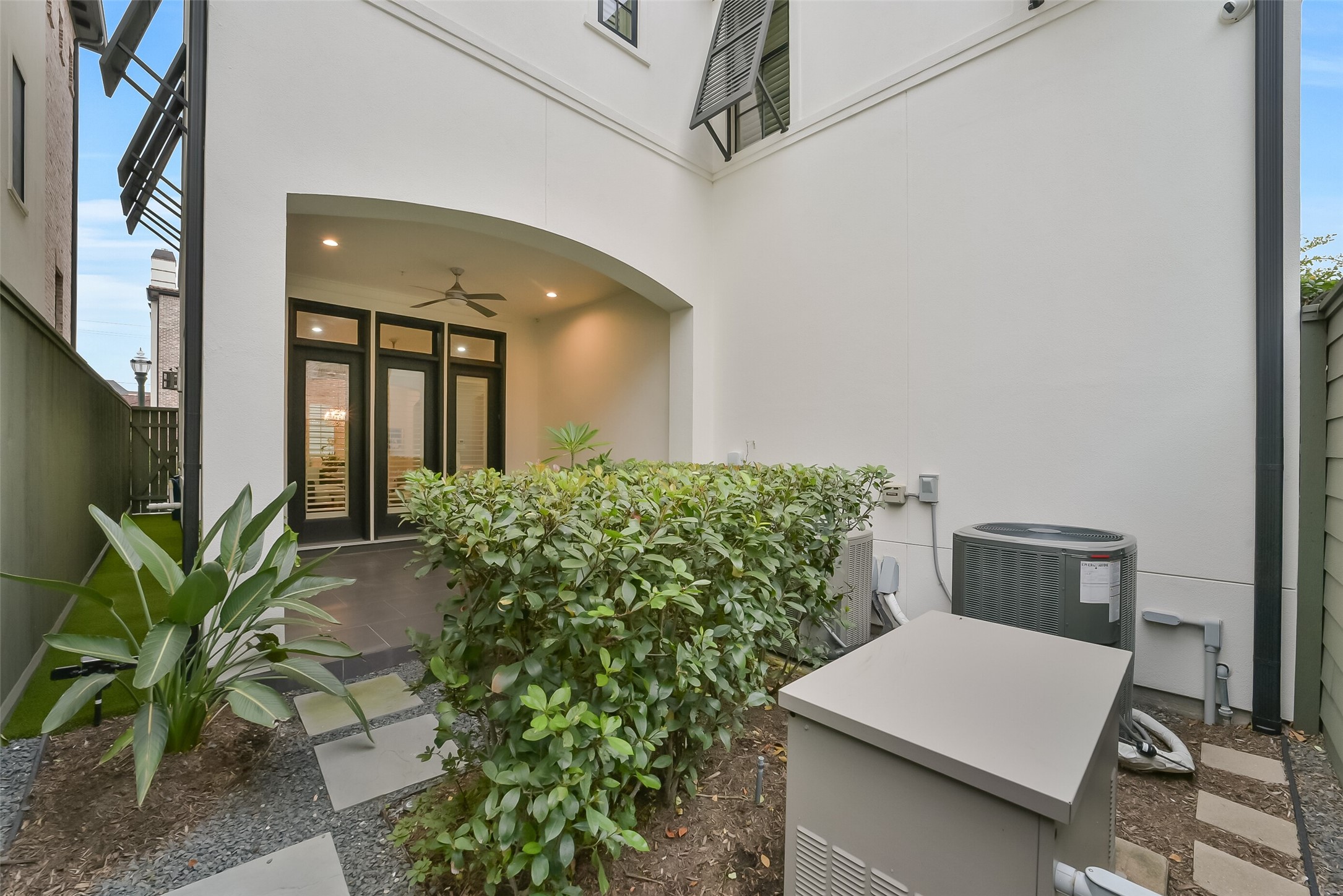 Private courtyard with a covered patio, ceiling fan, and French doors that open right into the living area. Low-maintenance landscaping, artificial turf, and stepping-stone pathways keep things tidy. A whole-home generator and water filtration system add peace of mind and everyday comfort.