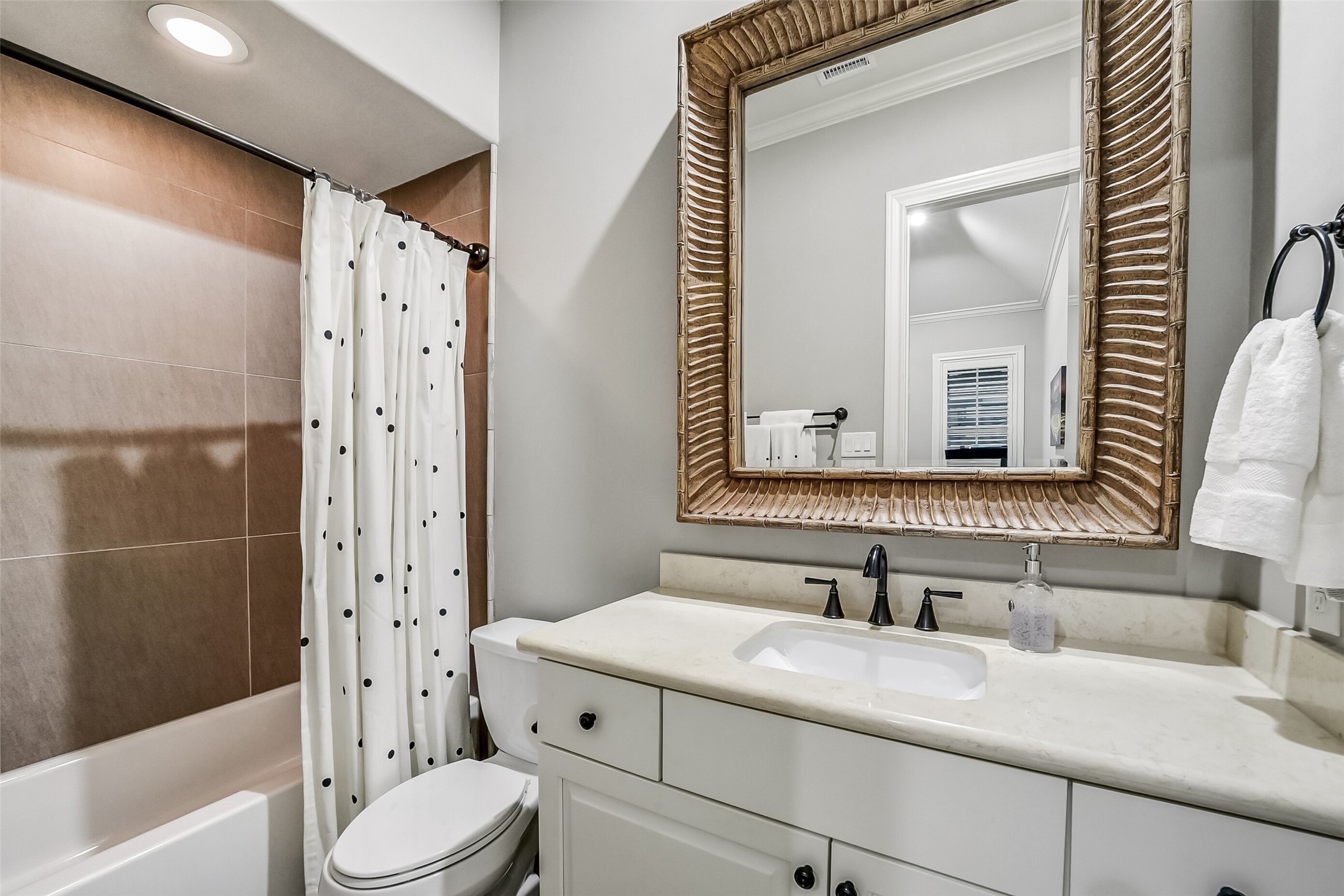 Private ensuite bath offers comfort and style for a secondary bedroom, featuring a vanity with beautifully framed mirror and tub/shower combo.