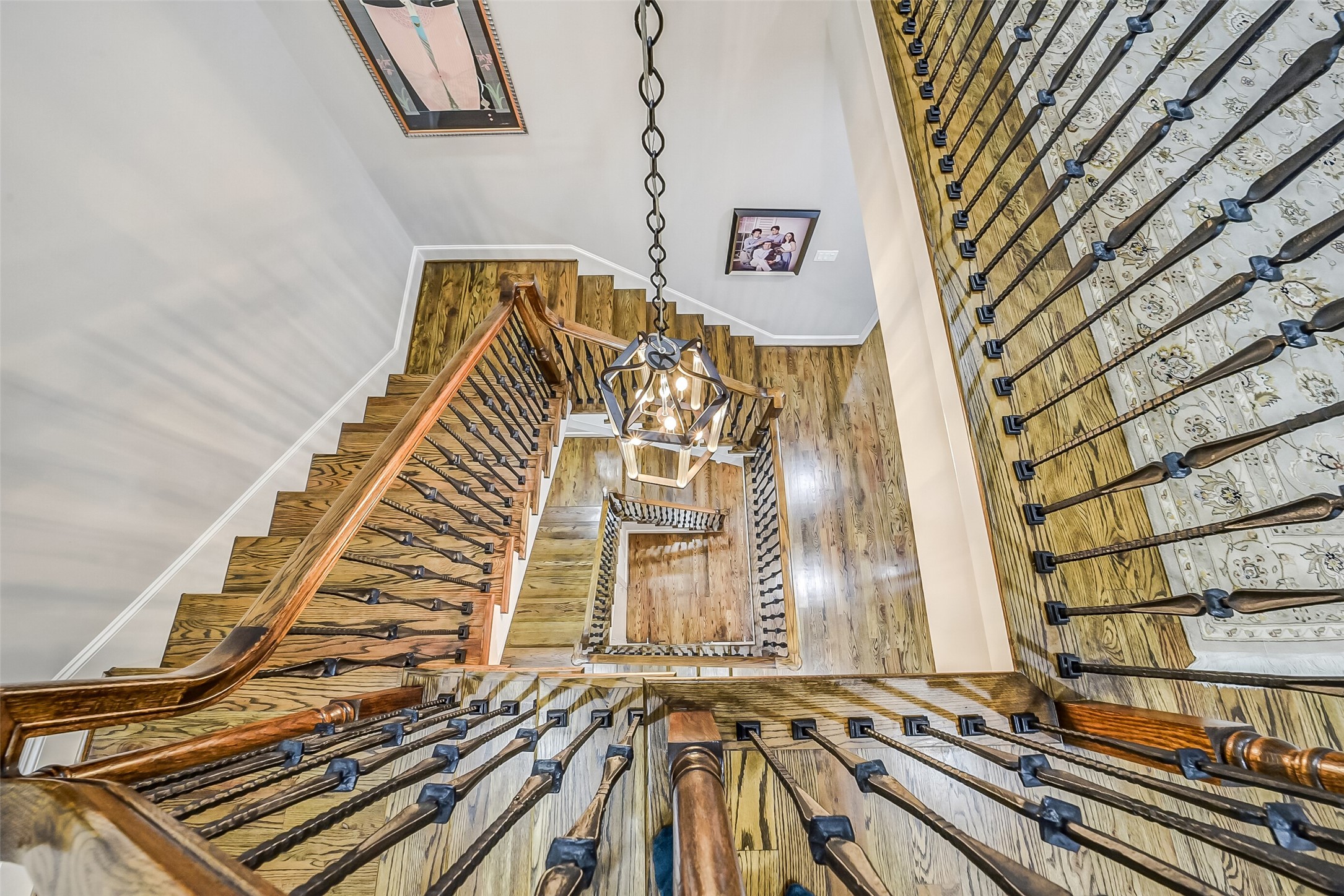 Striking perspective looking down the multi-level staircase, showcasing the rich hardwood treads, intricate wrought-iron and wood railings, and the home's exceptional vertical architectural flow.