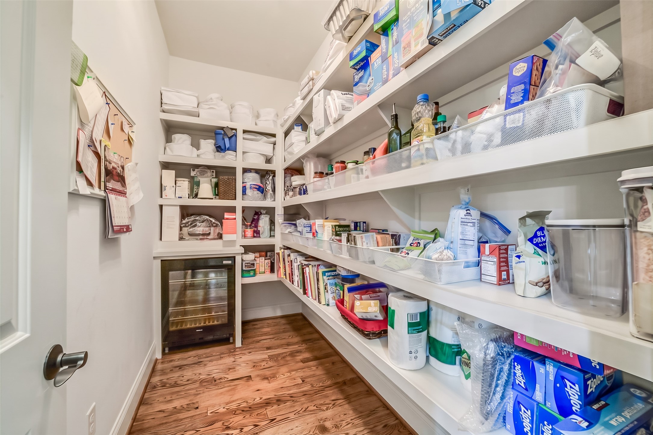Walk-in pantry with custom built-in shelving and a built-in wine refrigerator.