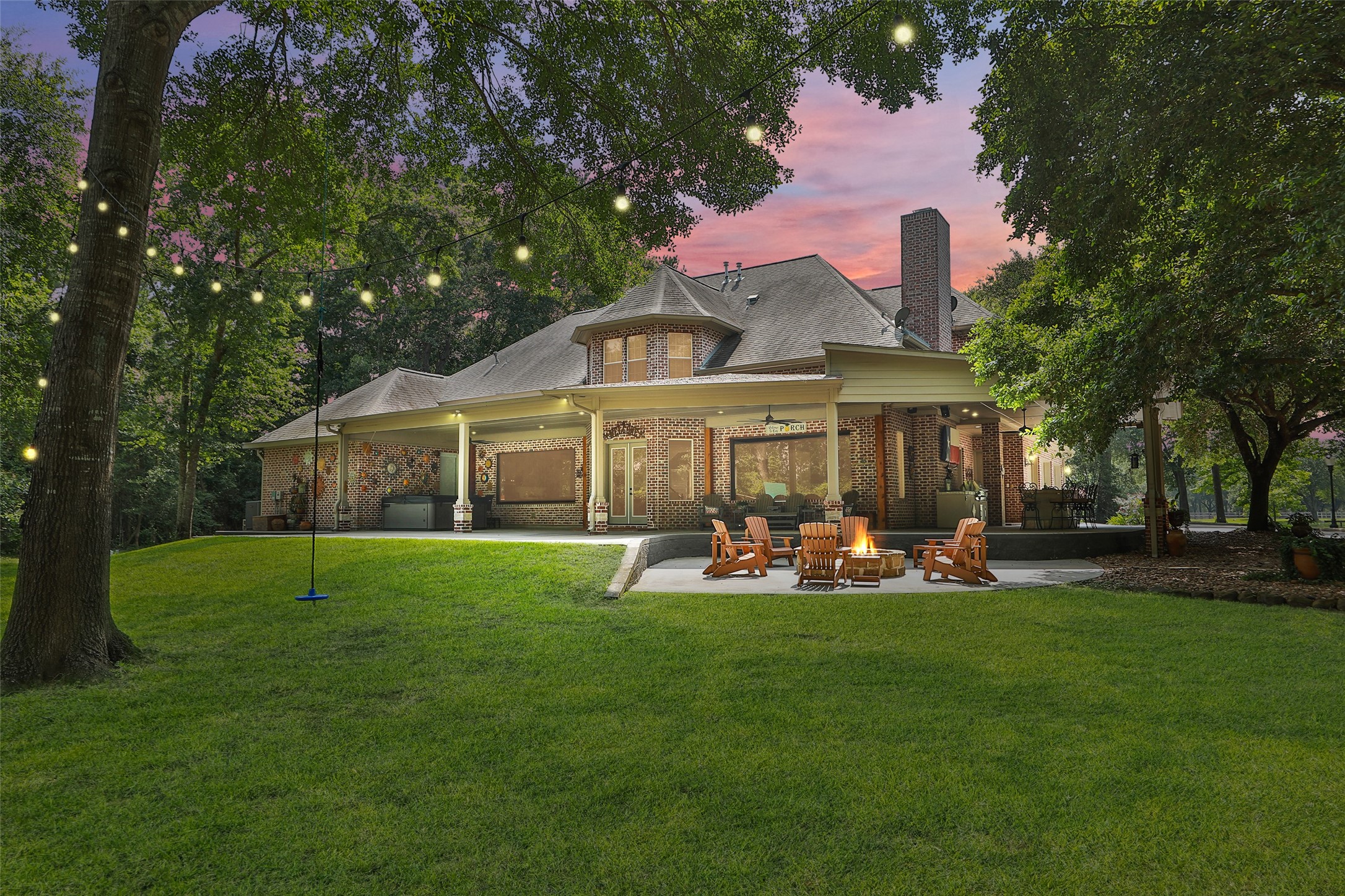 A view of the back of the house with an outdoor kitchen, 8 person hot tub on a 64 x 32 covered porch. Walk down a few steps into an escape for the evening with a firepit.