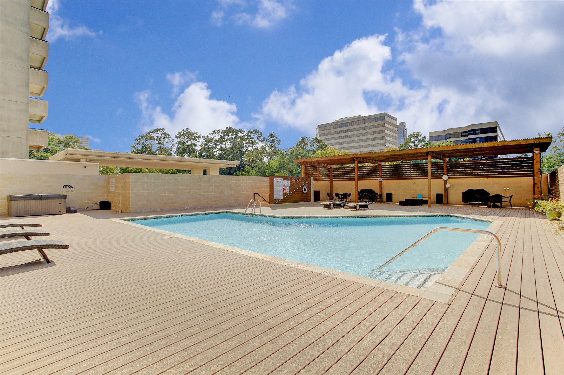 Pool area with covered pergola, hot tub and grills.