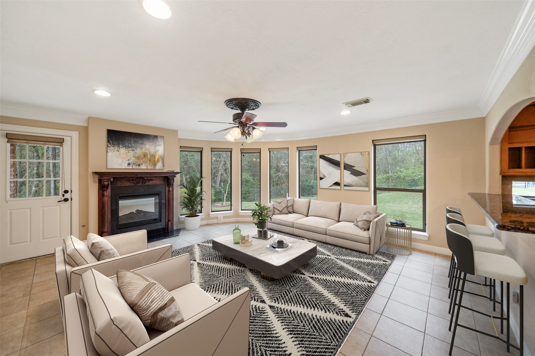 Spacious living room with large windows offering plenty of natural light. Features a cozy fireplace, modern ceiling fan, and elegant tile flooring. Virtually Staged living area adjacent to breakfast bar with stools. Spacious living room with large windows offering plenty of natural light. Features a cozy fireplace, modern ceiling fan, and elegant tile flooring. Virtually Staged living area adjacent to breakfast bar with stools.