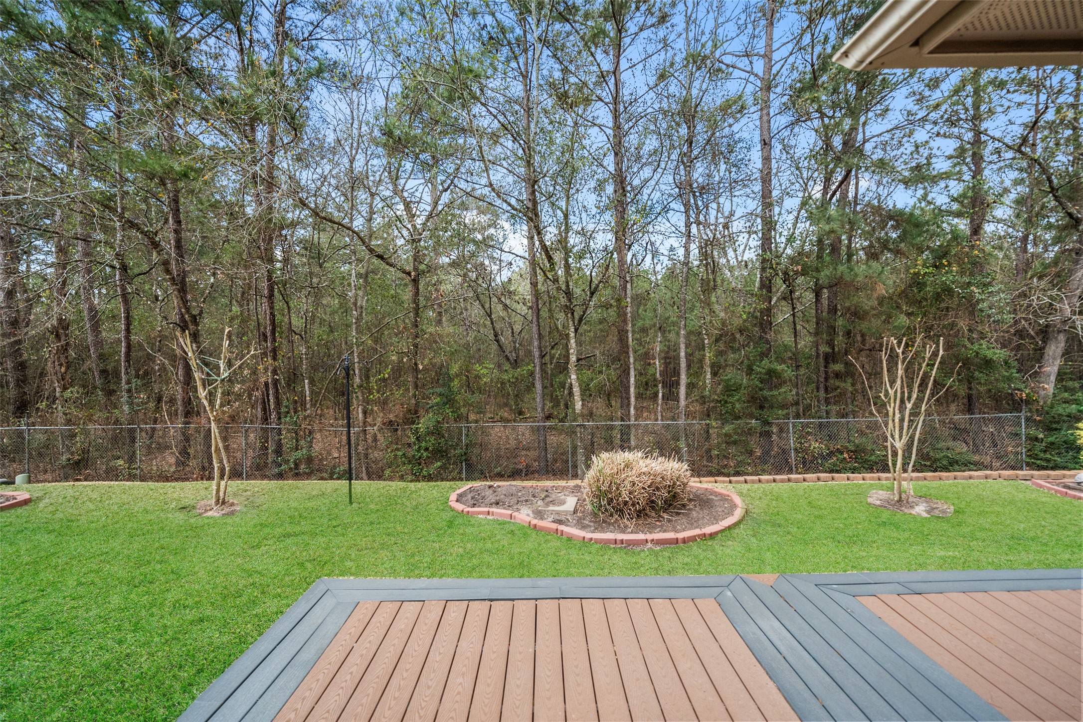 Spacious backyard with a well-maintained lawn, an extended deck, and a backdrop of lush trees, providing a serene and private outdoor space.