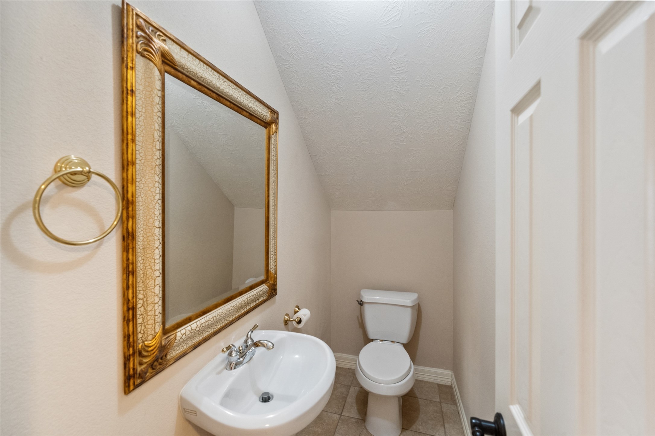 This is a compact half-bathroom with a pedestal sink and a large decorative mirror on the wall.