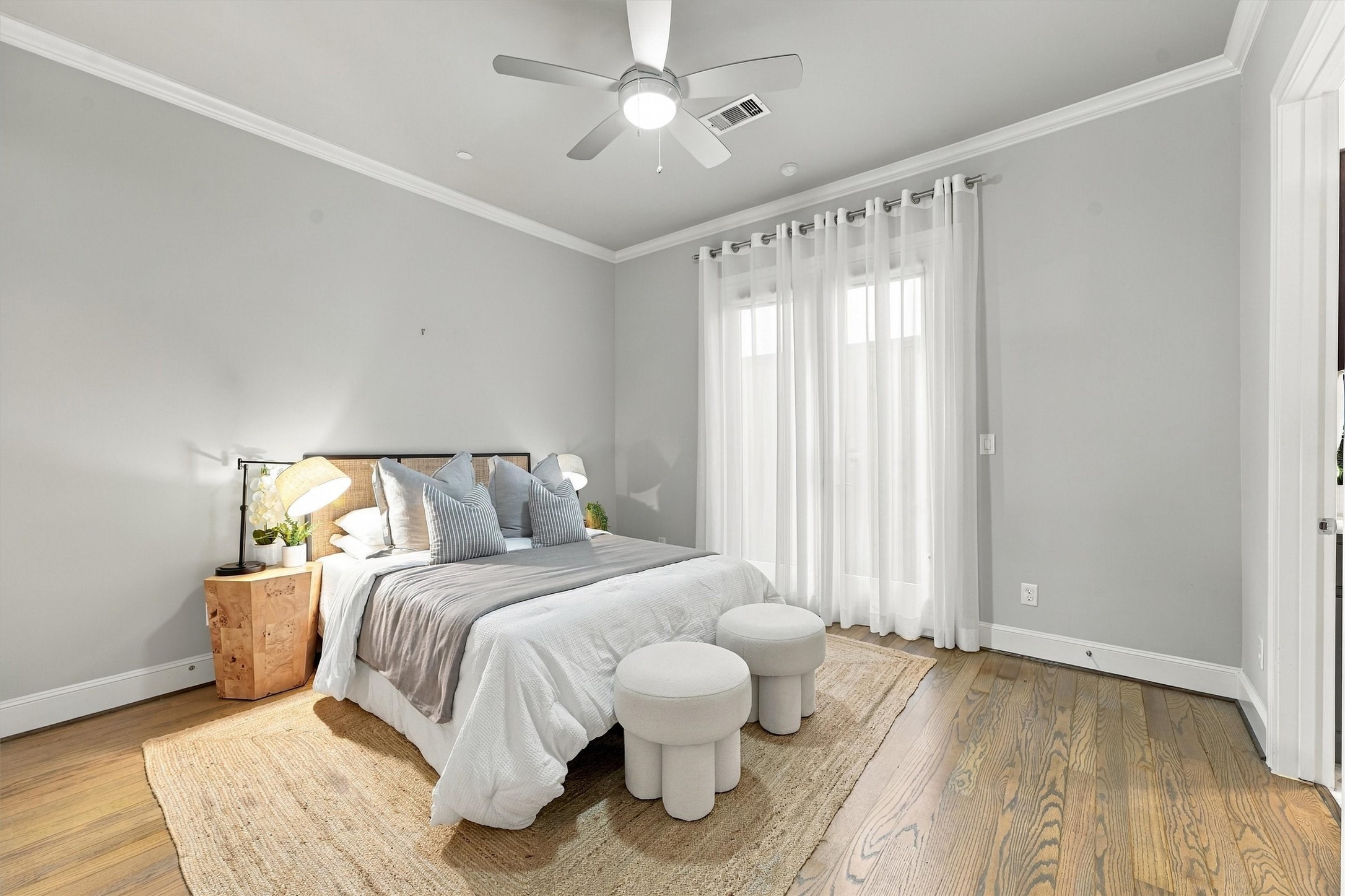 First-floor guest suite with floor-to-ceiling sheers and wood floors