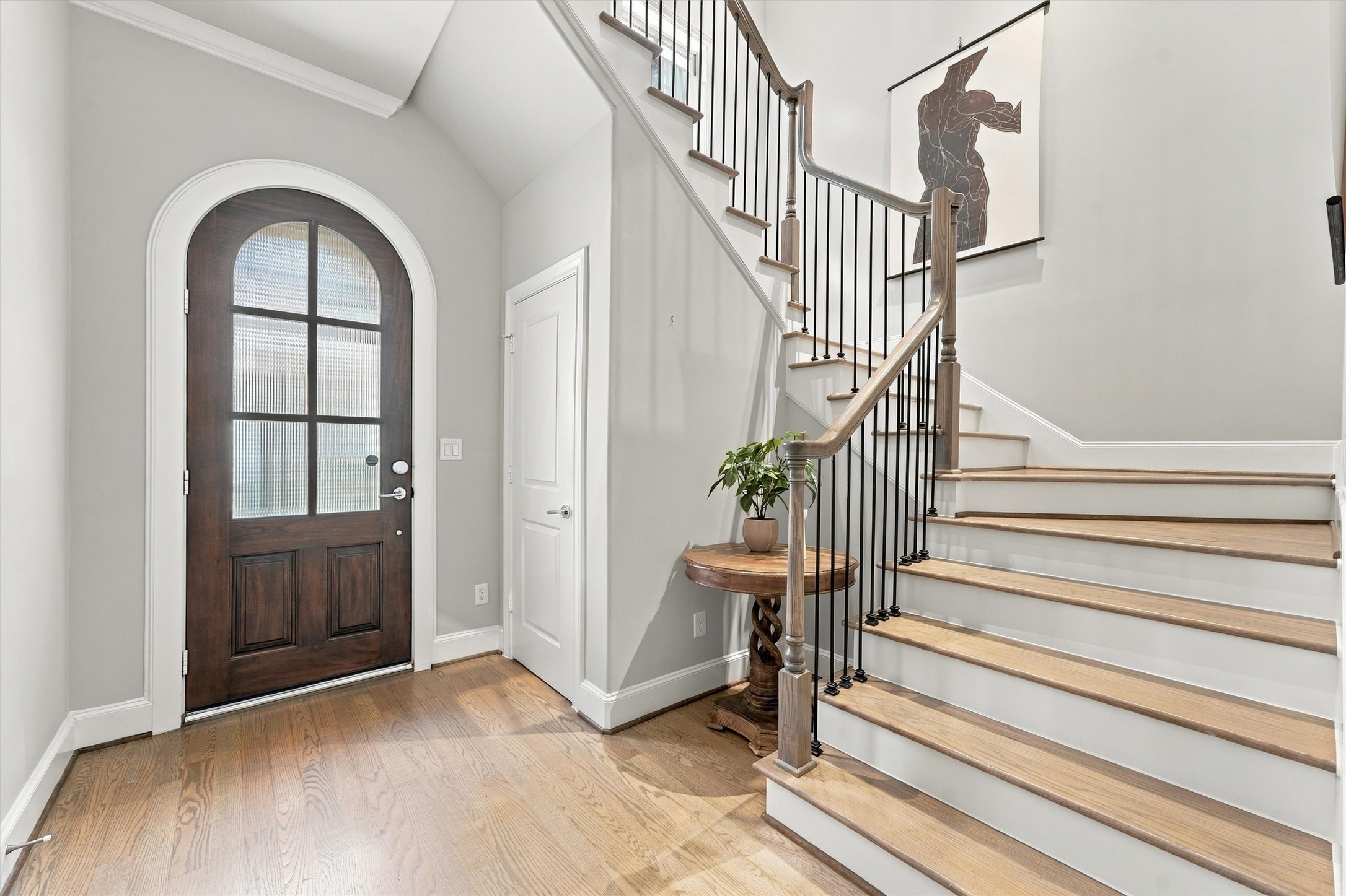 Foyer with a sculptural staircase of hardwood treads and wrought-iron spindles