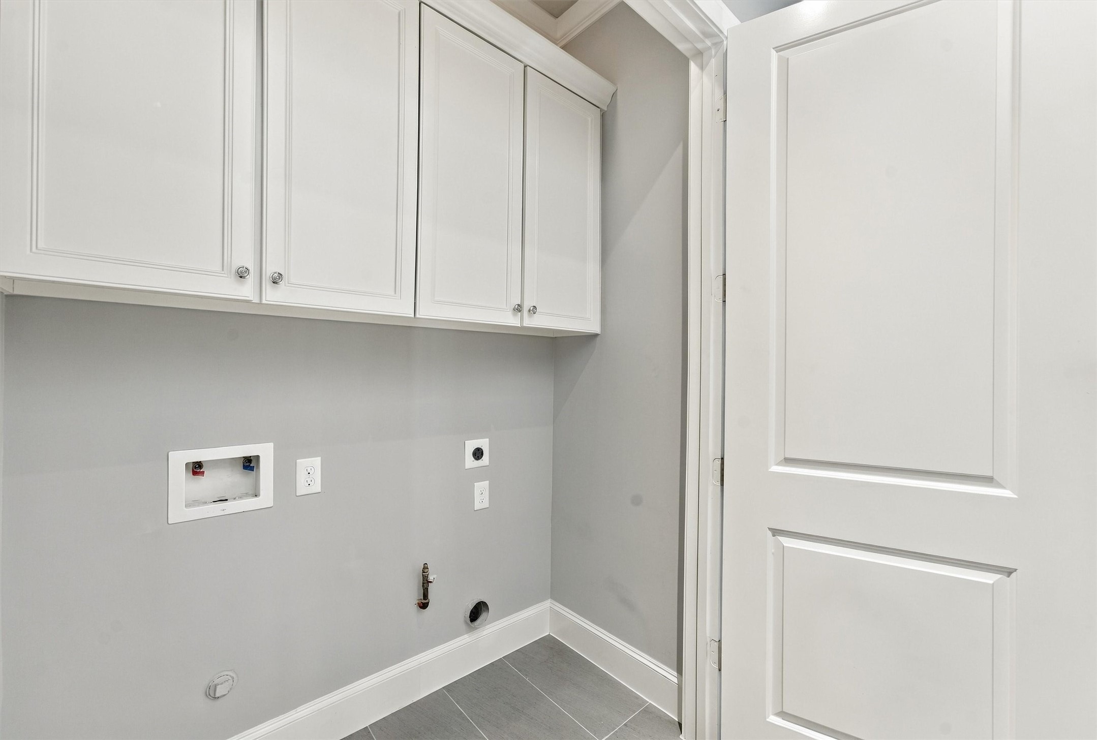 Utility room with full-size laundry connections and cabinetry above