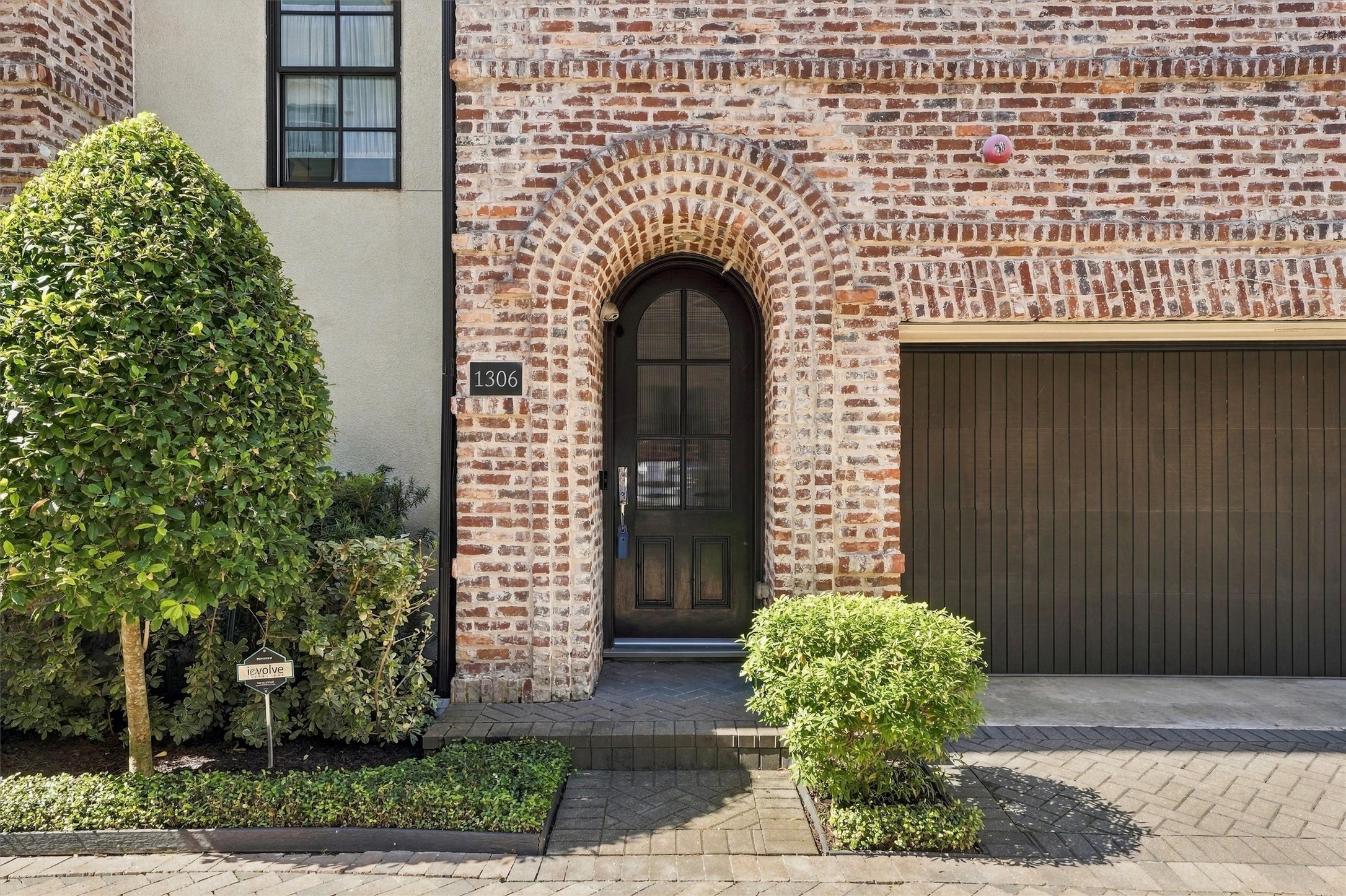 Arched eight-foot mahogany entry door set in a deep brick archway
