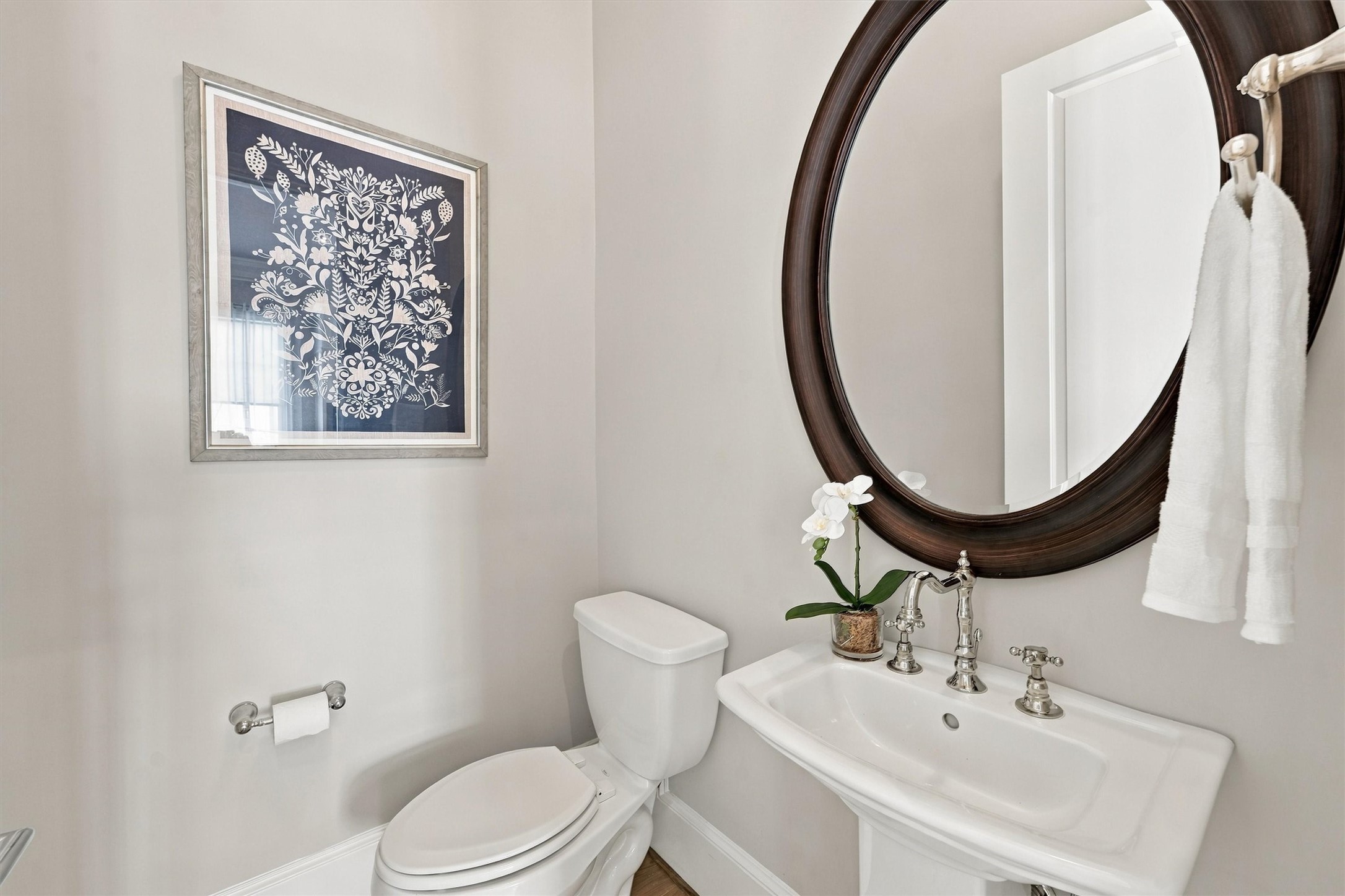 Powder room with a pedestal sink, cross-handle faucet and oval mirror