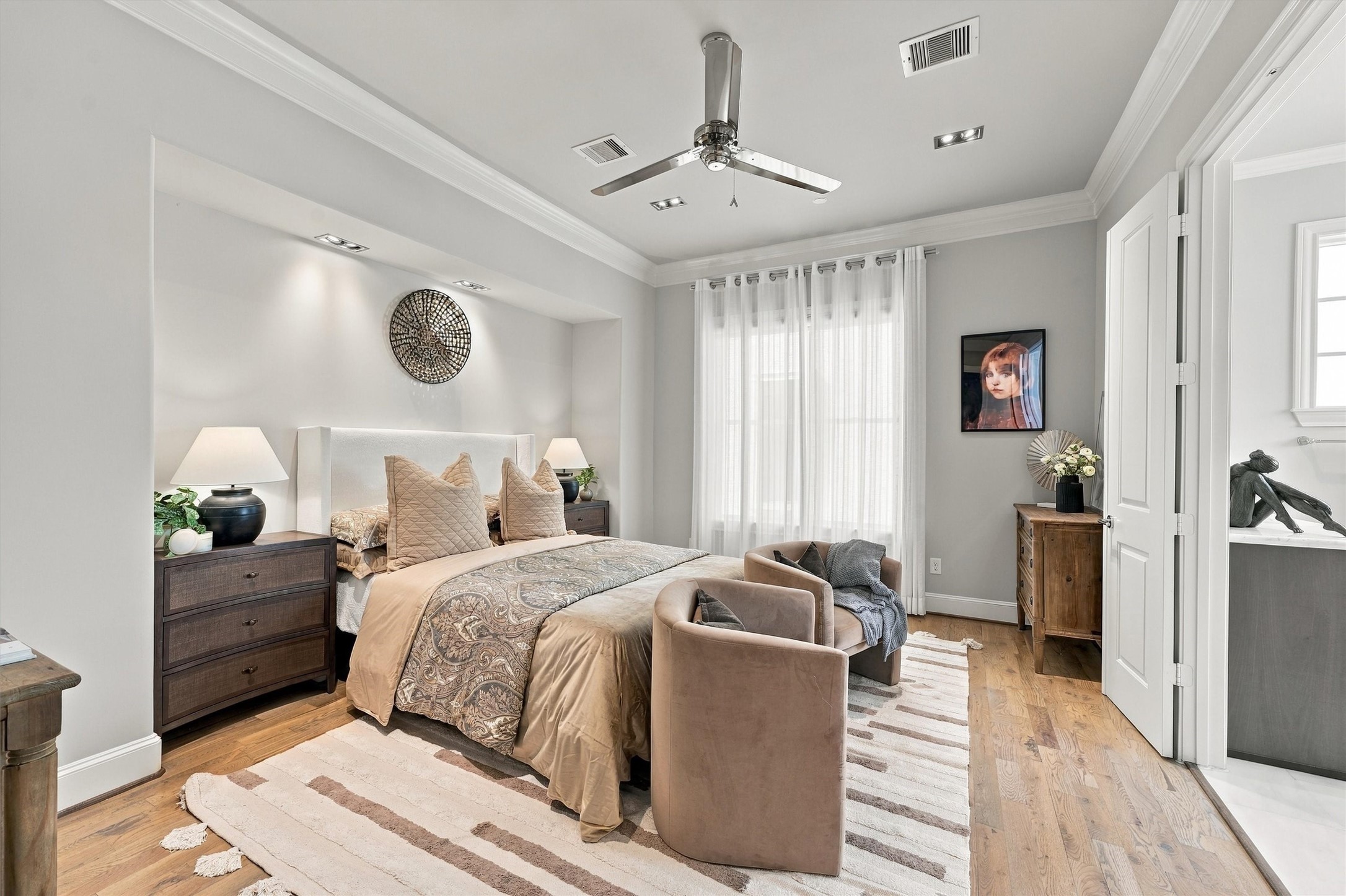 Primary suite with a softly lit alcove behind the bed and sheer-draped windows