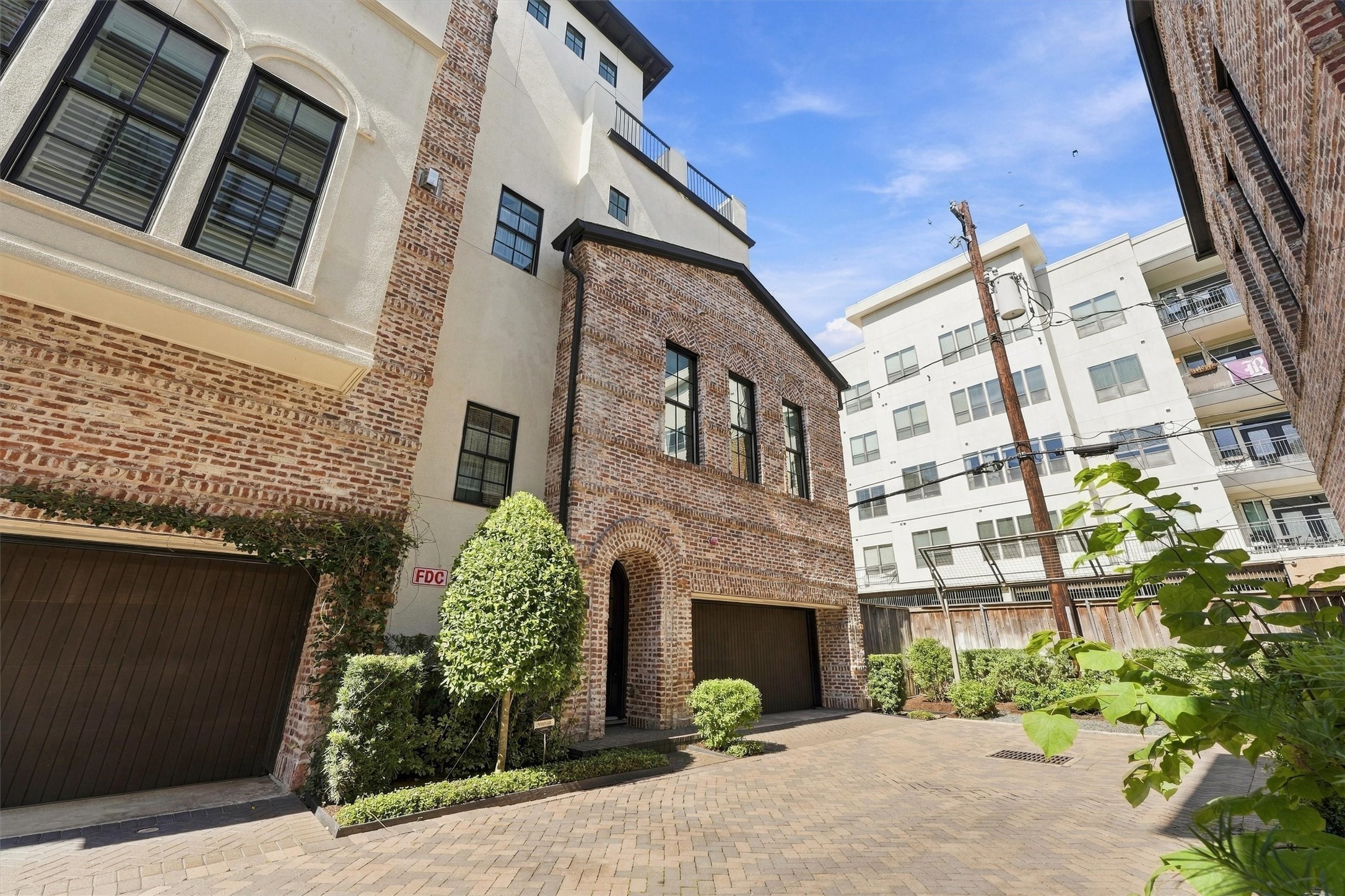 Four-story brick-and-stucco exterior with an attached garage tucked off the private drive.
