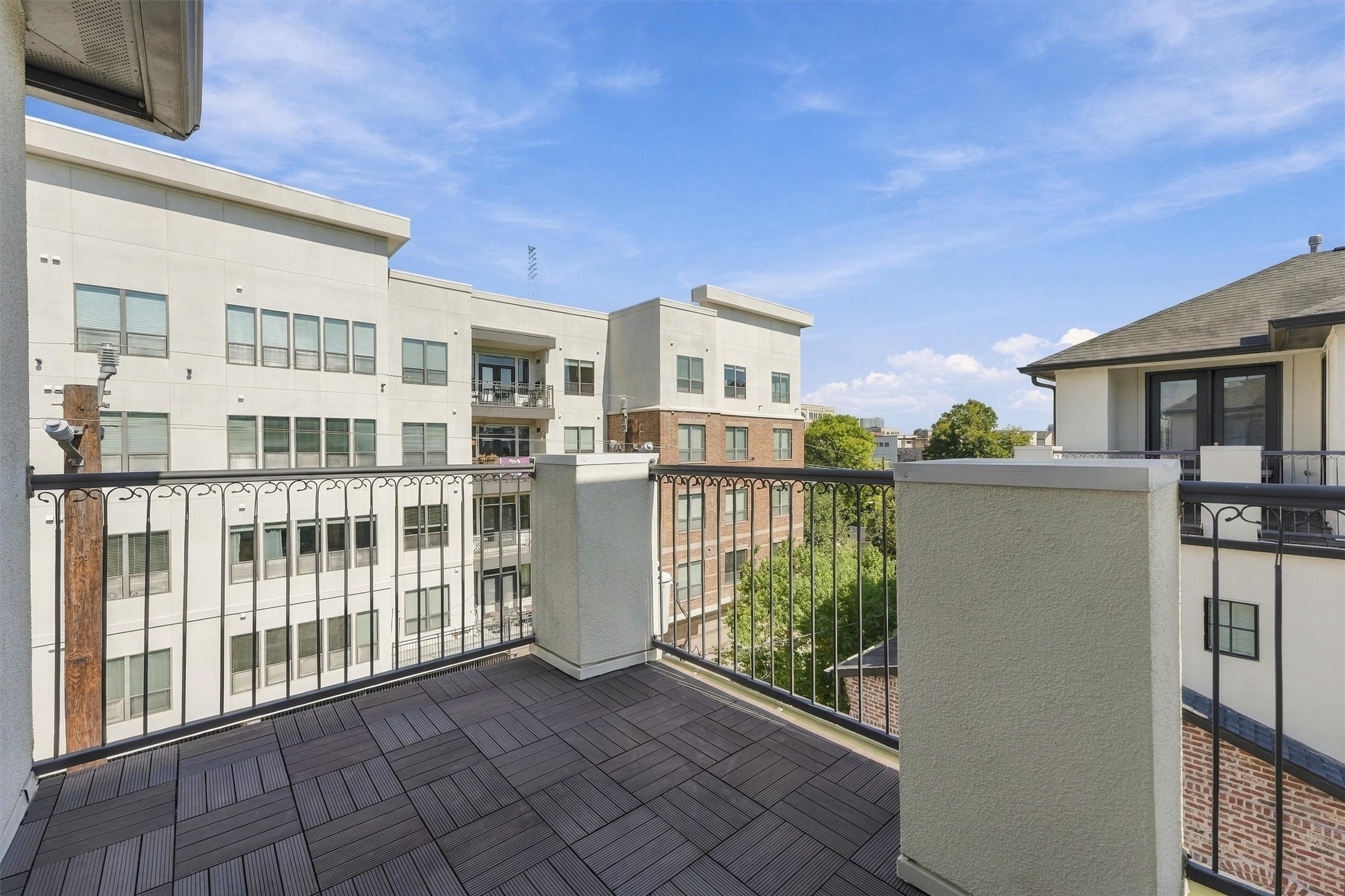 Fourth-floor terrace with a wrought-iron railing and neighborhood views