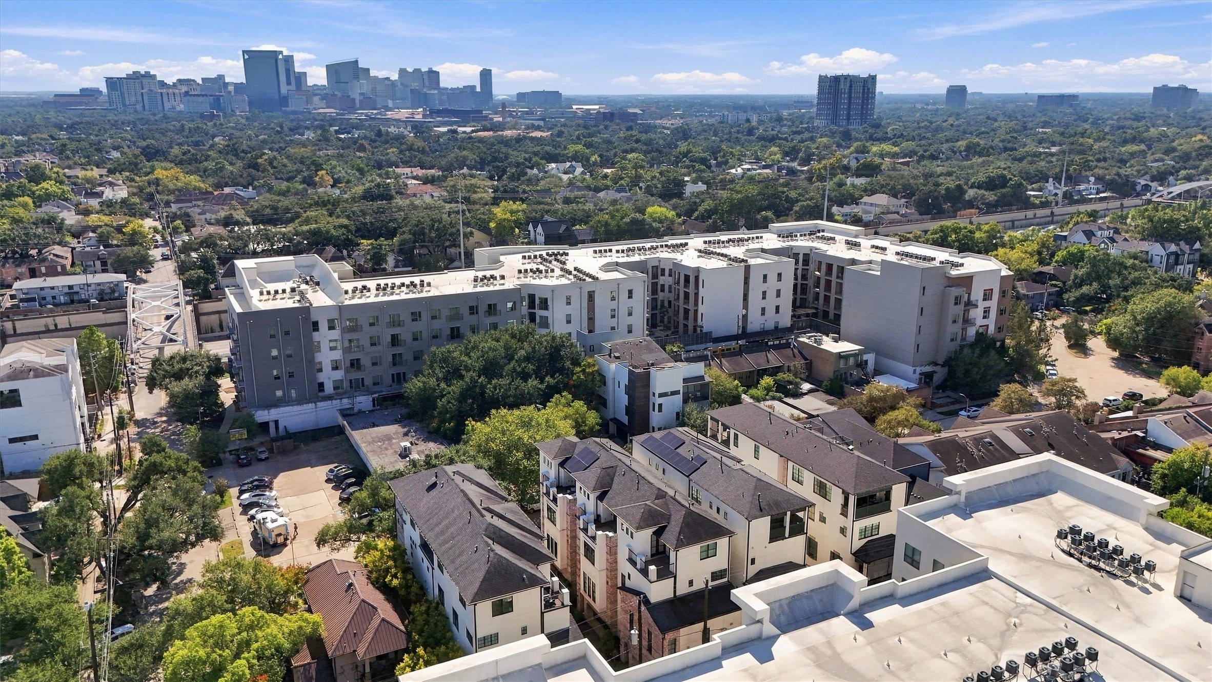 Montrose rooftops beneath a mature tree canopy, with the city skyline beyond