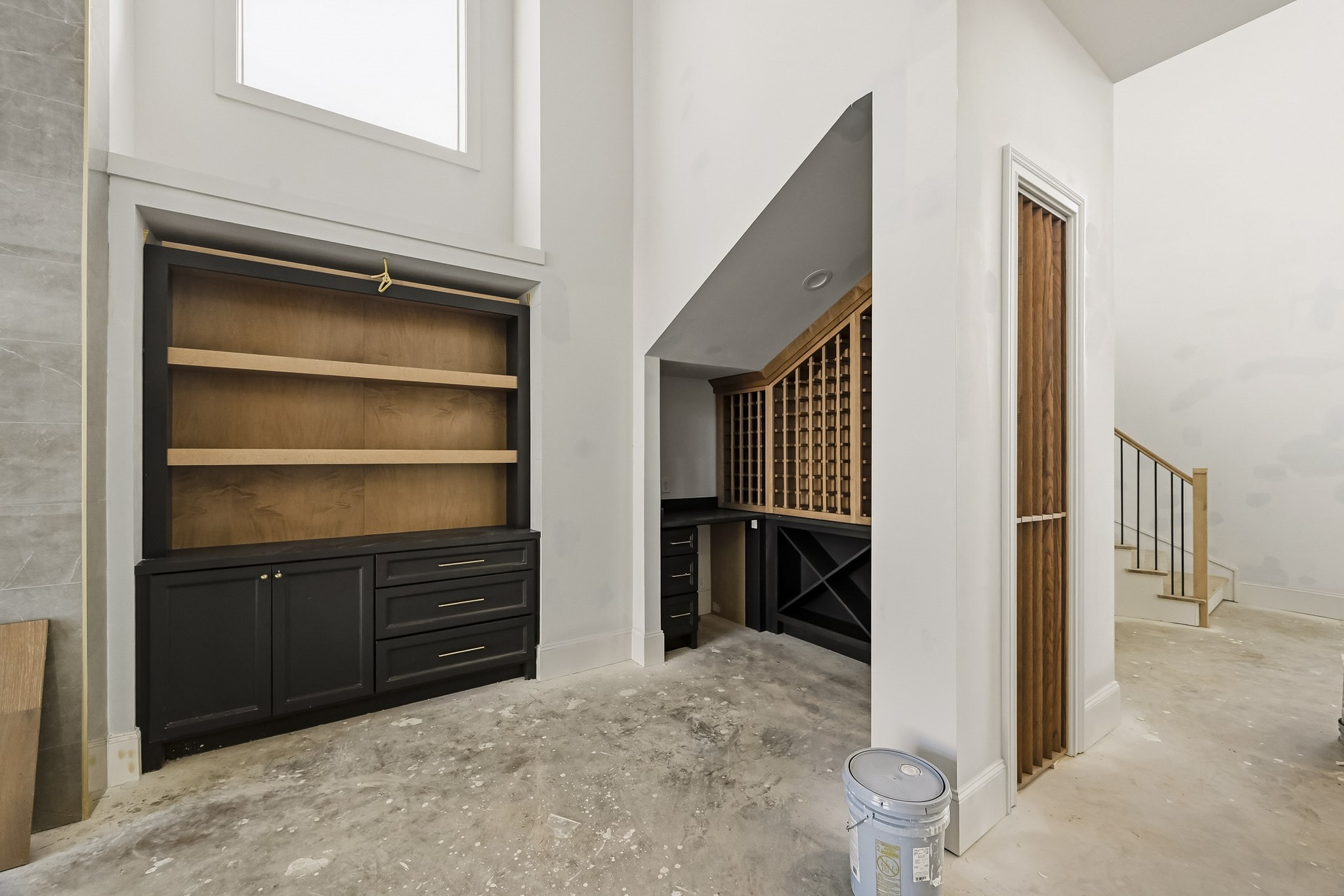 Elegant built-in cabinetry and a spacious wine rack create a sophisticated atmosphere, complemented by high ceilings and an open staircase design!