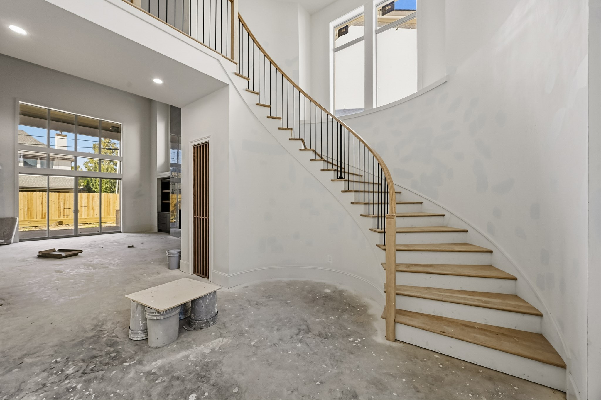 A grand, sweeping staircase leads to an upper level, complemented by large, sunlit windows and an open-concept living area, ready for customization!