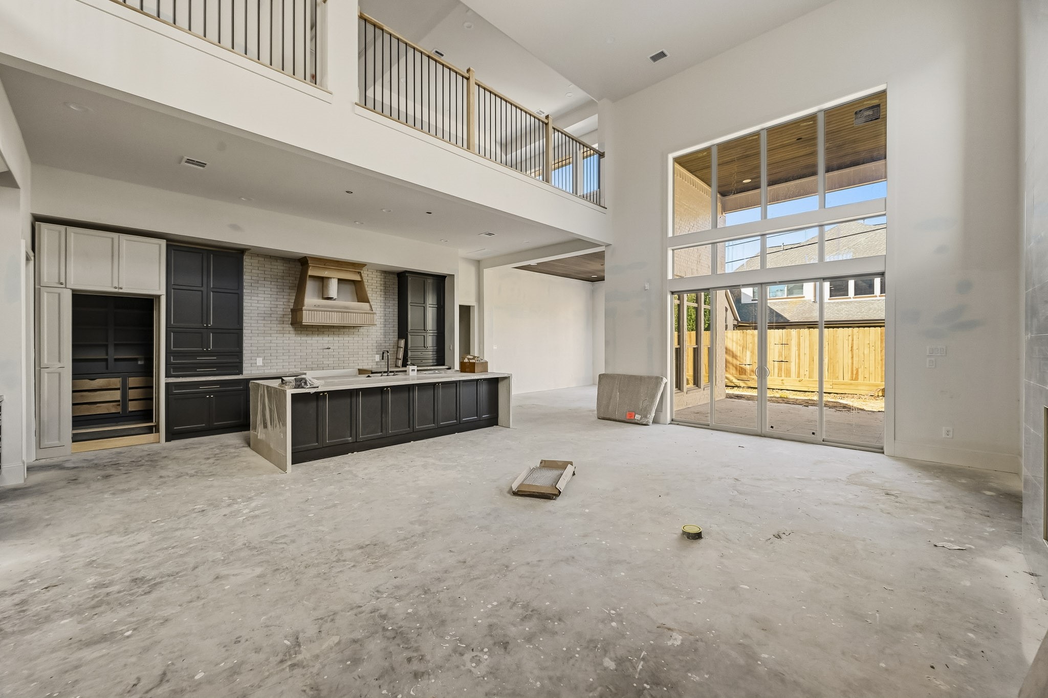 Stunning open-concept living area with soaring ceilings, expansive windows, and a sleek modern kitchen complete with chic cabinetry and a large island!
