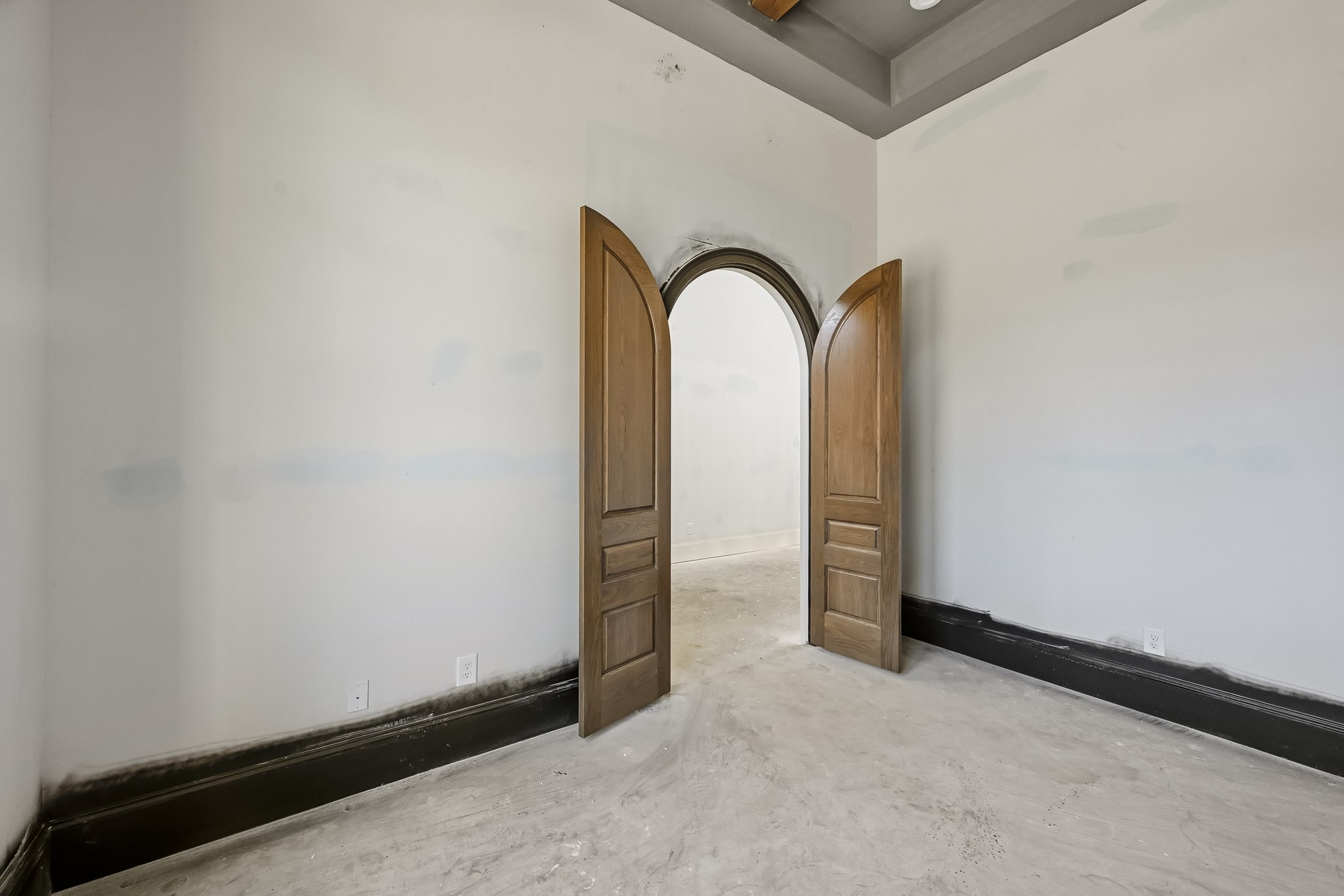 Elegant arched double doors add a touch of sophistication to this spacious study, enhanced by high ceilings and neutral tones!