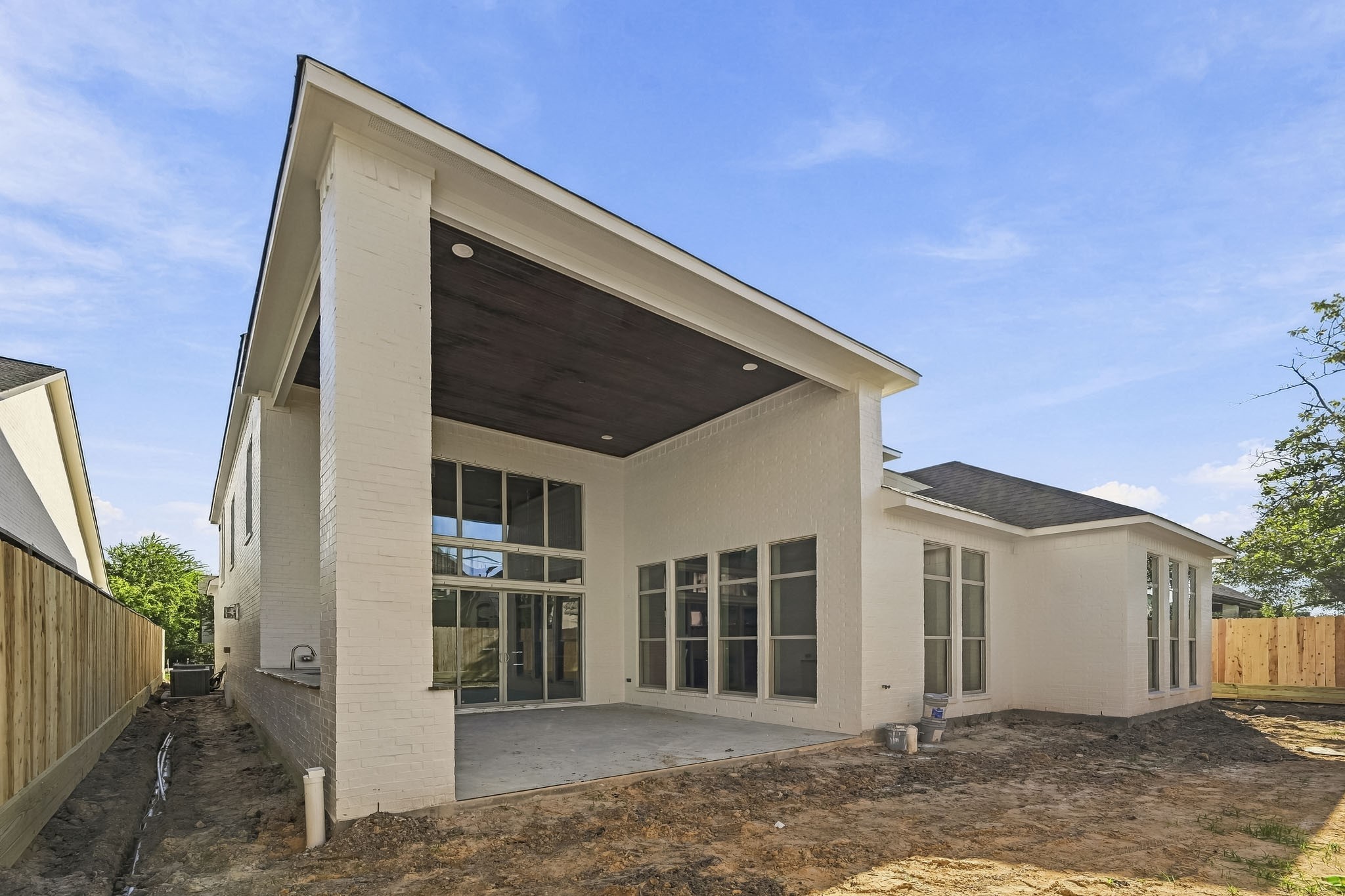 Modern home with a covered patio, large windows, and a fenced yard, perfect for outdoor entertaining!