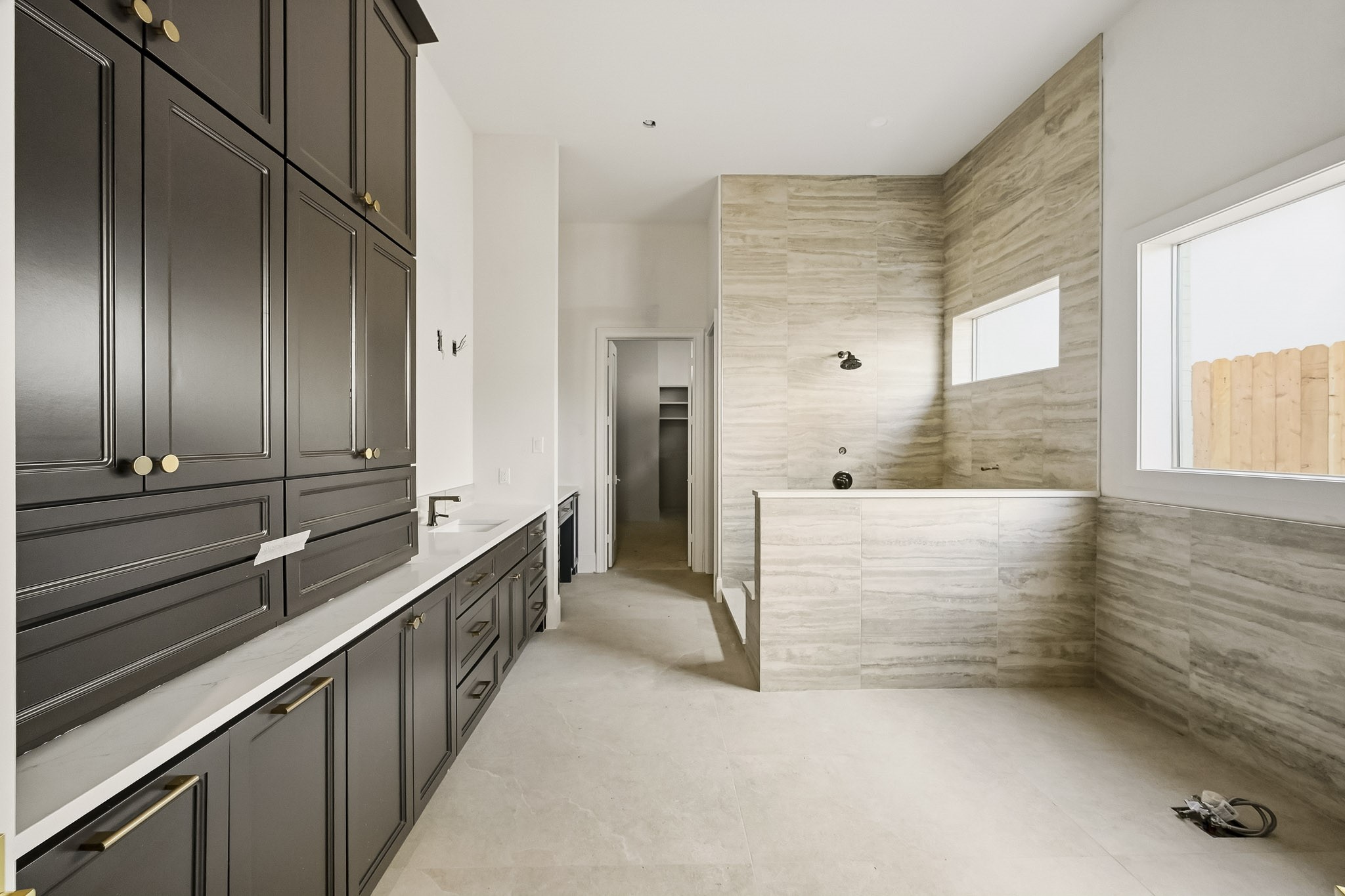 Primary ensuite featuring elegant dark cabinetry, plenty of counter space, and a stylish tiled area with large windows for natural light!