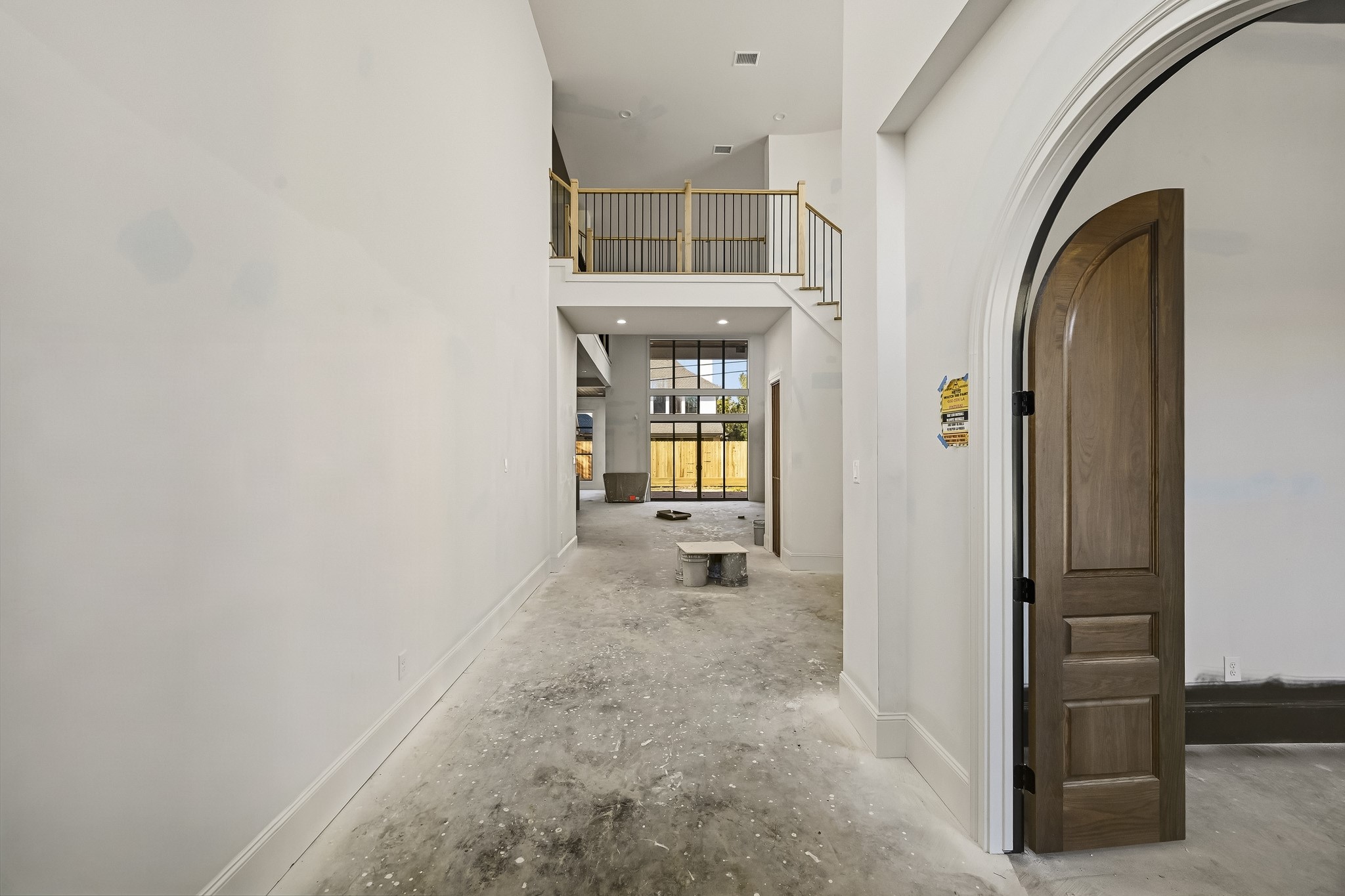 Expansive entryway with soaring ceilings and an elegant arched doorway, leading to a bright, open living space with large windows and a view of the backyard!