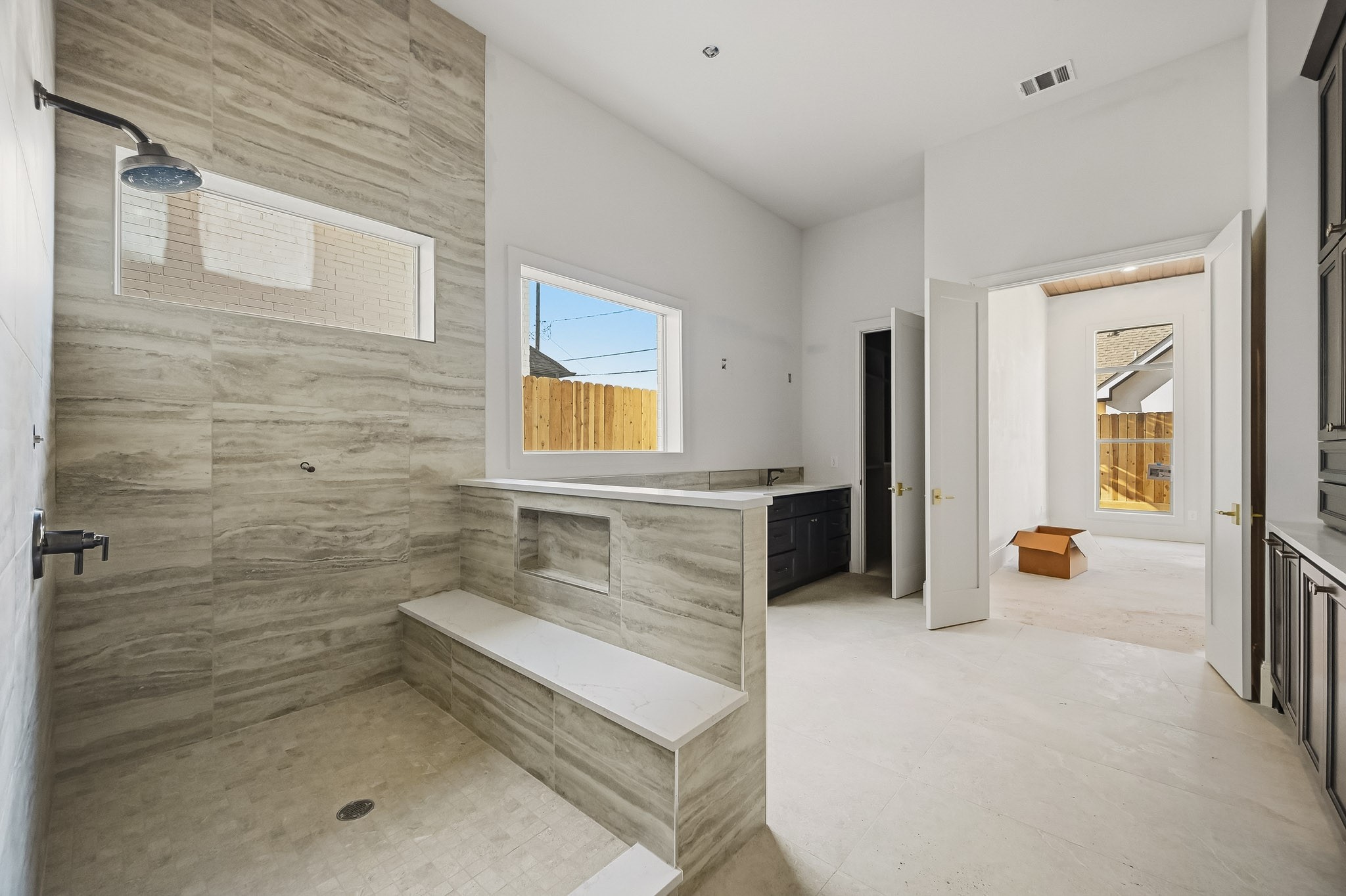 Bright and airy bathroom featuring a large, tiled walk-in shower with a convenient built-in bench and modern fixtures, complemented by  a stylish vanity area!
