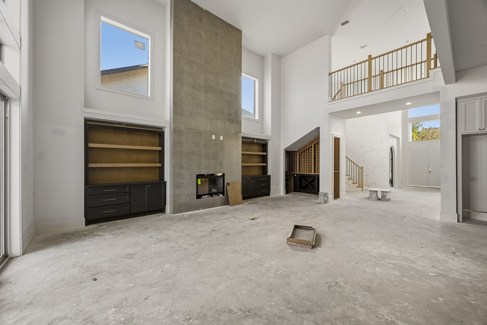 Airy living area with high ceilings and large windows, featuring a modern fireplace and built-in shelving, offering a bright and open atmosphere!