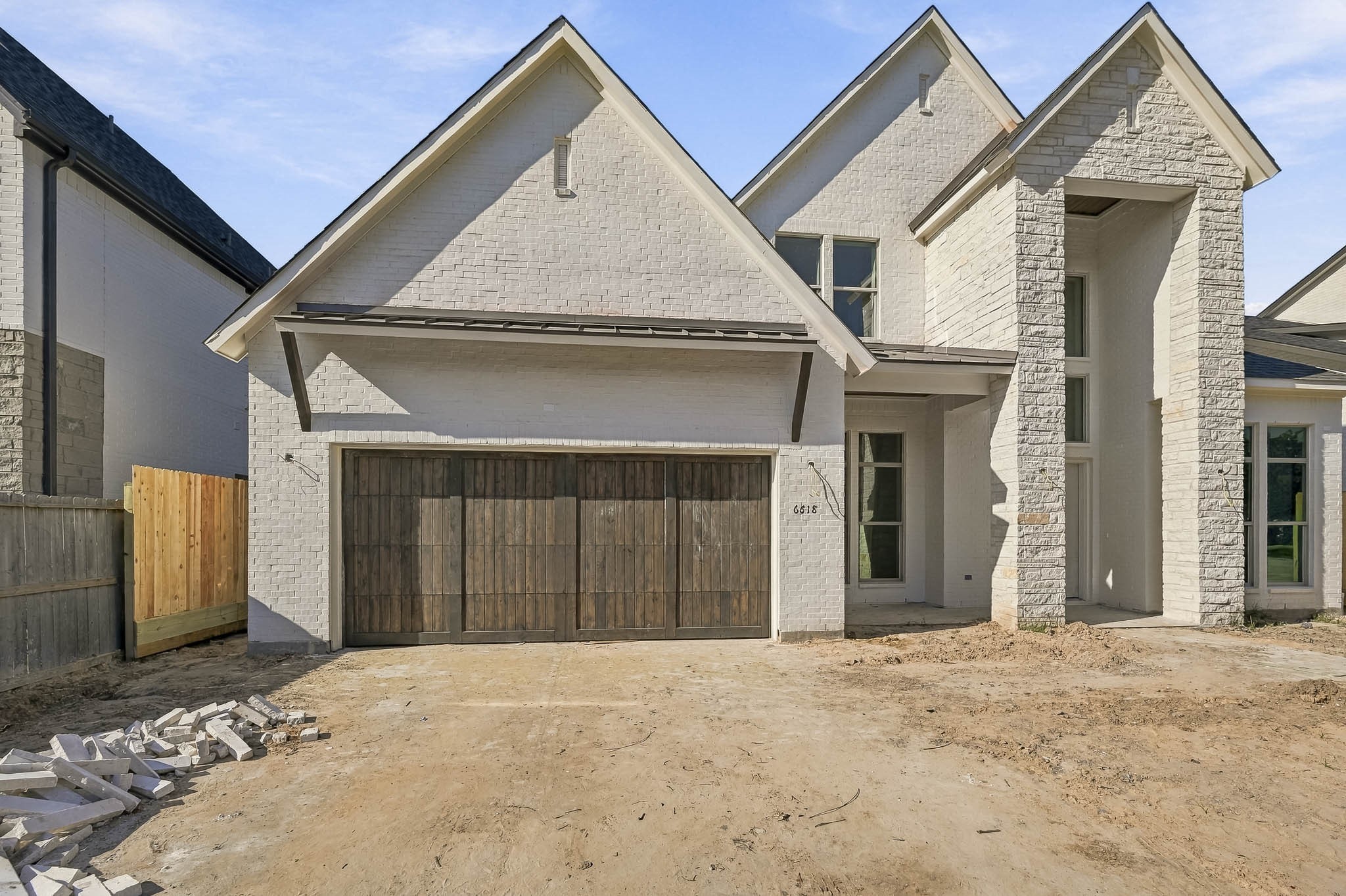 Stunning new construction featuring a modern brick exterior with a rustic wooden garage door, offering a blend of contemporary design and timeless charm!