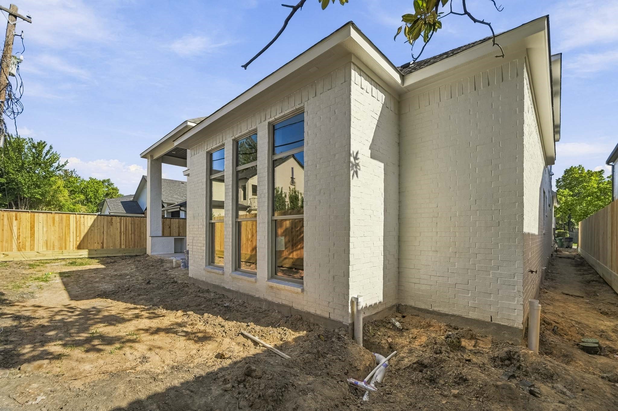 Charming home with a sleek white brick exterior, large windows, and a spacious backyard.