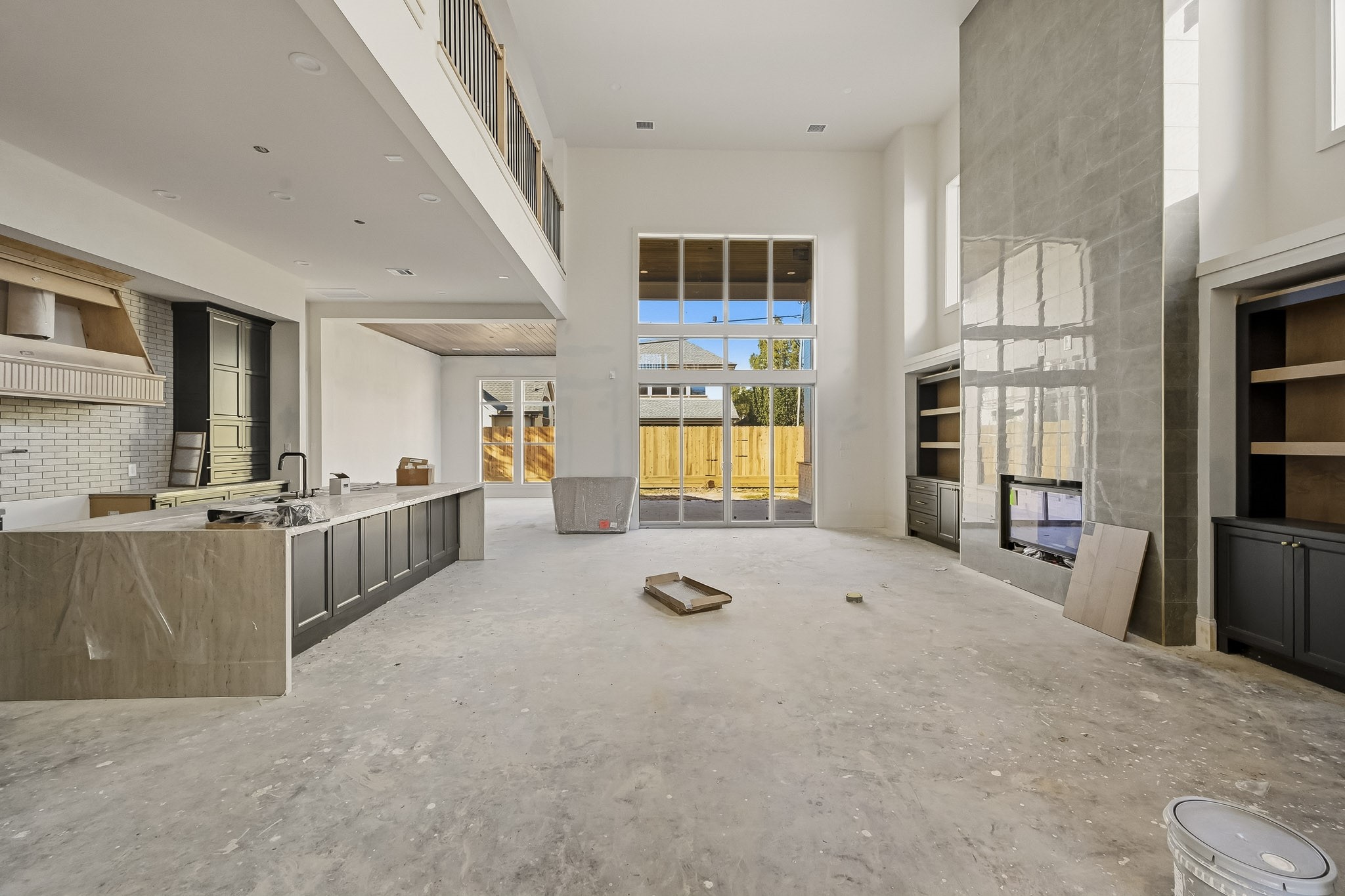 Stunning two-story living area with expansive windows, a sleek fireplace, and a modern open-plan kitchen, perfect for entertaining and relaxation!