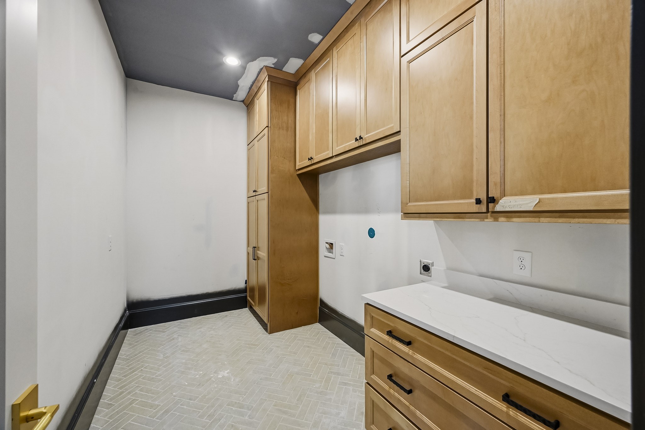 Large laundry room featuring ample wooden cabinetry for storage, sleek countertops, and modern fixtures, perfect for laundry and organization!