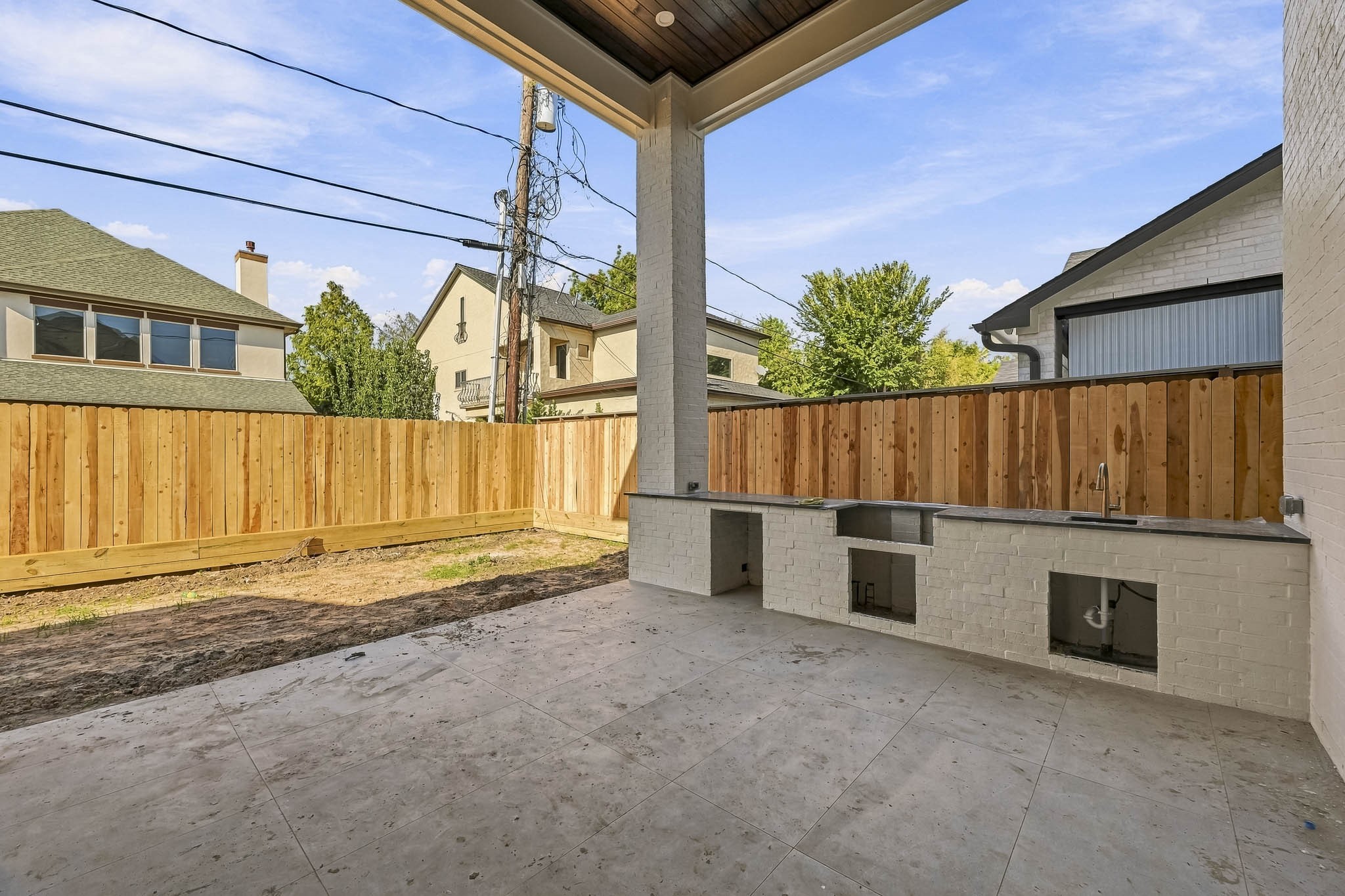 Covered patio featuring a built-in outdoor kitchen area, perfect for entertaining, with a view of a fenced backyard for privacy!