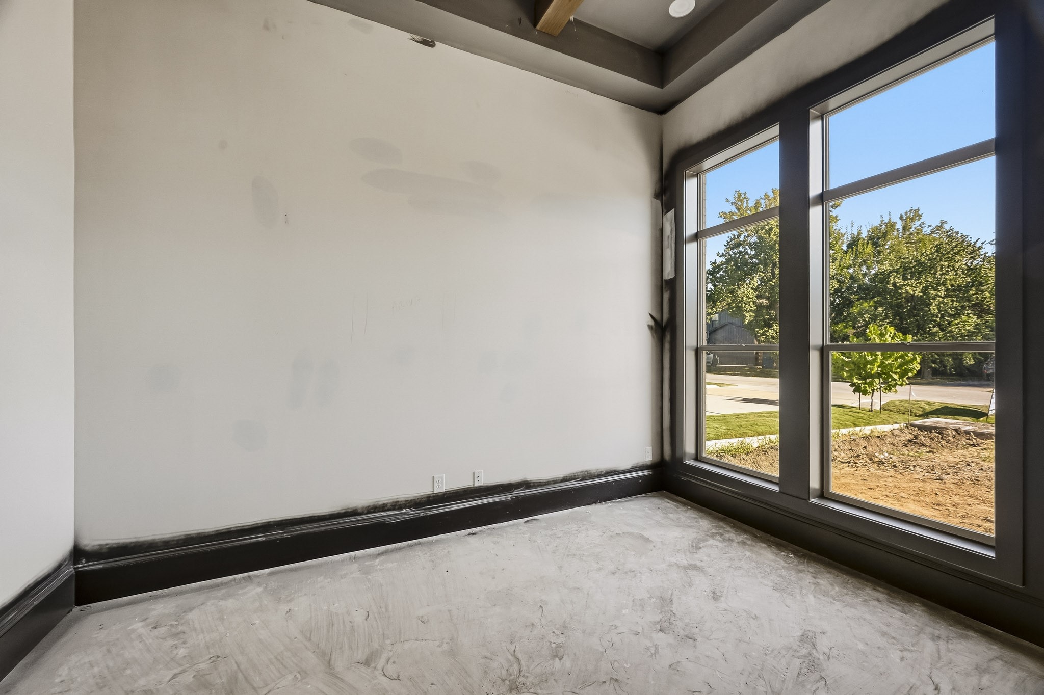 Bright study with large windows offering plenty of natural light and a view of the outdoors, featuring sleek dark trim for a modern touch!