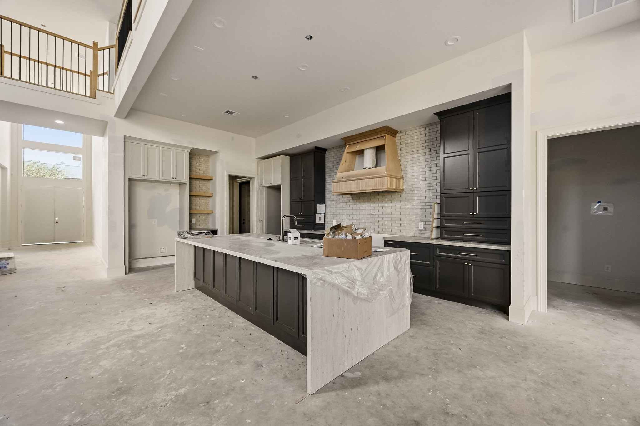 Spacious modern kitchen featuring elegant dark cabinetry, a large island with marble countertop, and high ceilings for an airy feel!