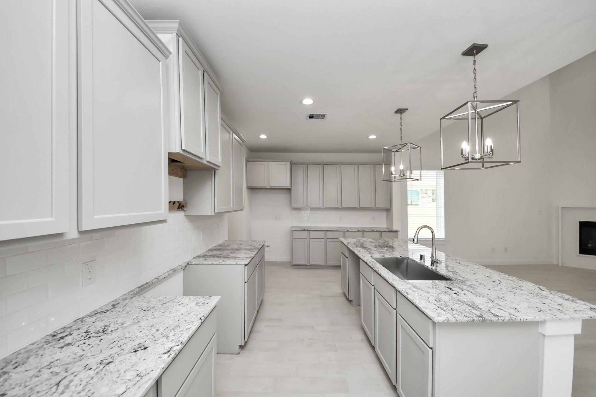 This generously spacious kitchen is a dream realized! With a massive granite island, high ceilings, soft close cabinets, granite countertops, stainless steel appliances, a sleek tile backsplash, recessed lighting, and an extended counter area, it offers both style and practicality. All this opens up to the expansive family room, creating a perfect hub for gatherings. Sample photo of completed home with similar floor plan. Actual colors and selections may vary.