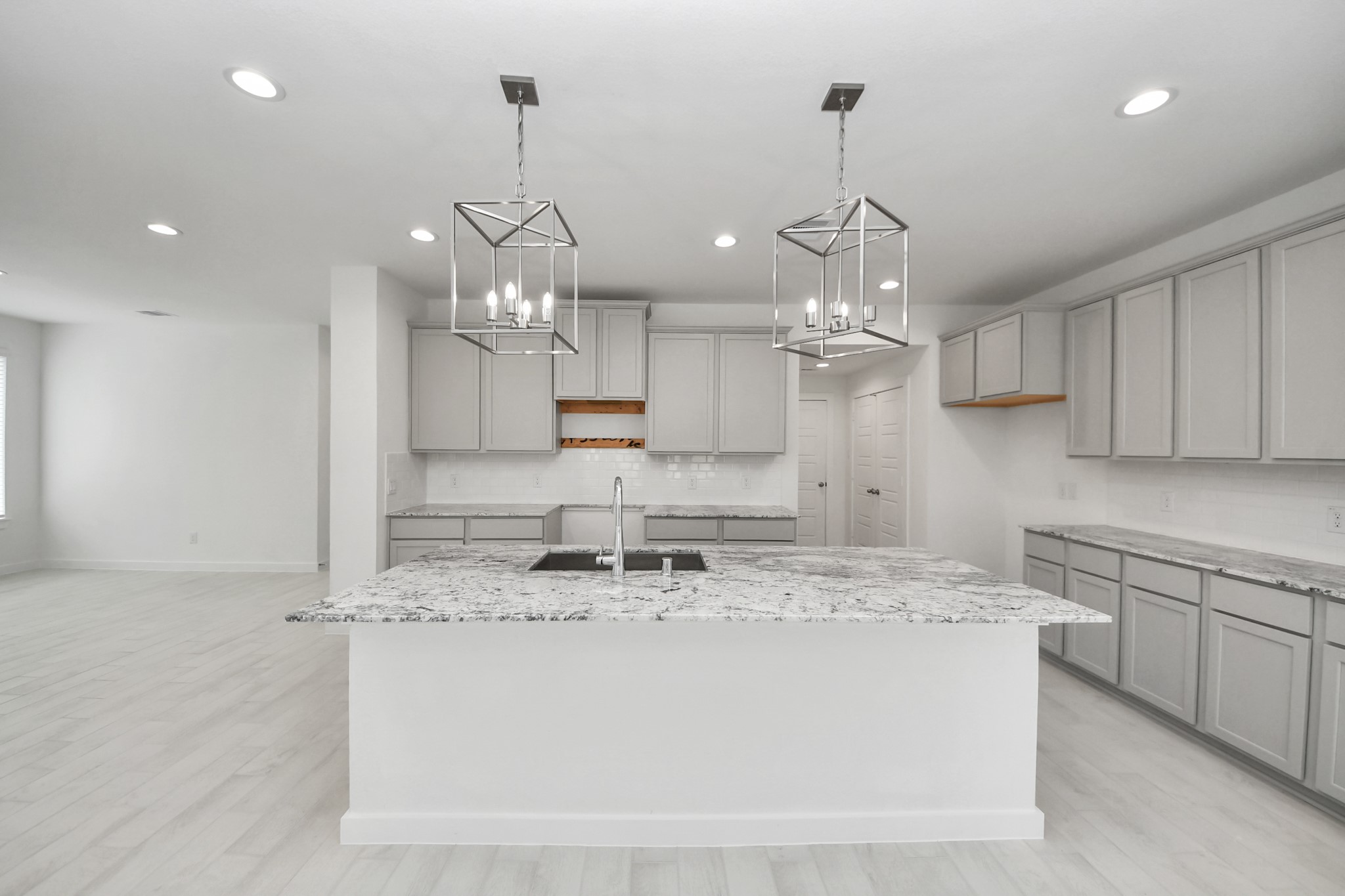 This kitchen is by far any chefs dream! This spacious kitchen features high ceilings, stained wood cabinets, granite countertop, SS appliances, modern tile backsplash, recessed lighting, extended counter space, granite kitchen island with double sink, and space for breakfast bar, and a walk-in pantry all overlooking your huge family room. Sample photo of completed home with similar floor plan. Actual colors and selections may vary.