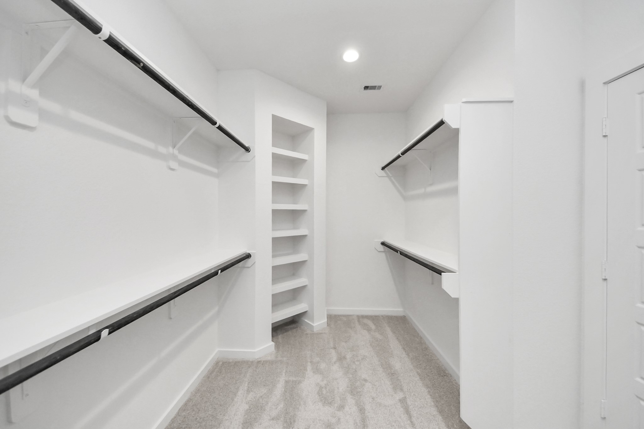 Walk-in closet that epitomizes luxury and practicality. This generously sized space features built-in shelving, offering abundant room for impeccable organization. High ceilings and recessed lighting create a bright and welcoming ambiance. Sample photo of completed home with similar floor plan. Actual colors and selections may vary.
