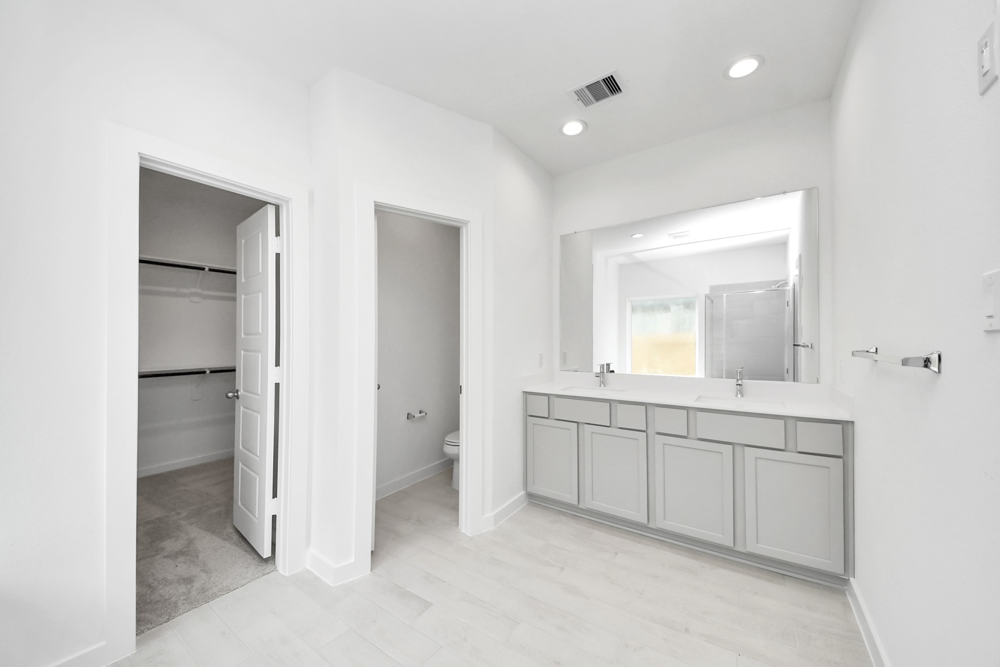 Elevate your daily routine at the elegant vanity, now equipped with double sinks, light countertops, modern hardware, and beautiful recessed lights. Sample photo of completed home with similar floor plan. Actual colors and selections may vary.