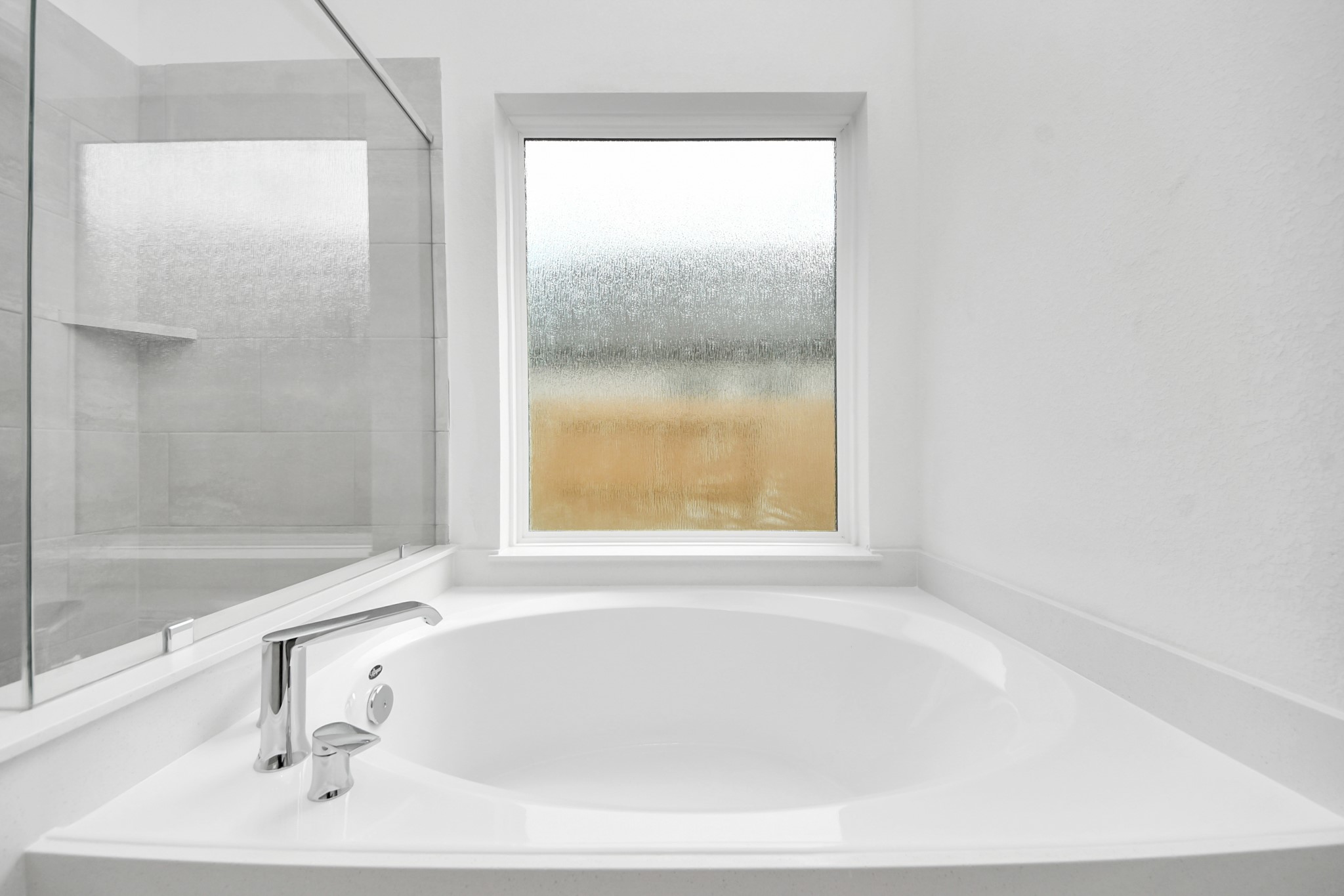 Indulge in a spa-like retreat within the confines of this primary bathroom. Delight in a spacious walk-in shower enveloped in stylish tile surround, unwind in a separate garden tub adorned with custom detailing. Sample photo of completed home with similar floor plan. Actual colors and selections may vary.