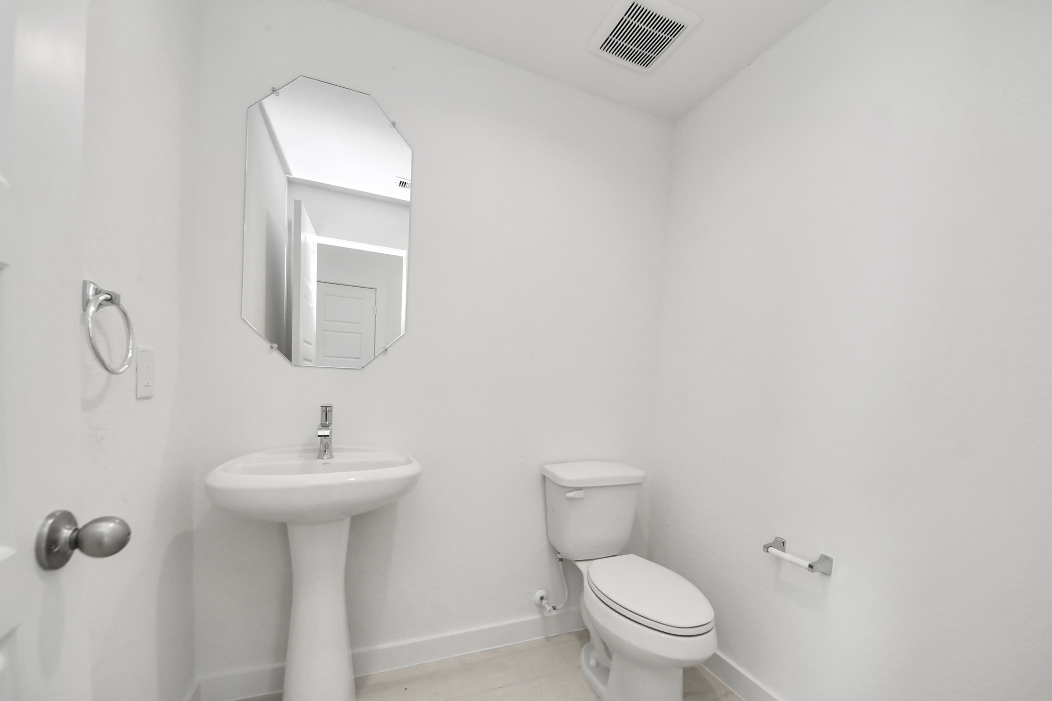This half bathroom features a stylish pedestal sink, modern hardware, and bright recessed lighting, creating a sleek and inviting space. Sample photo of completed home with similar floor plan. Actual colors and selections may vary.