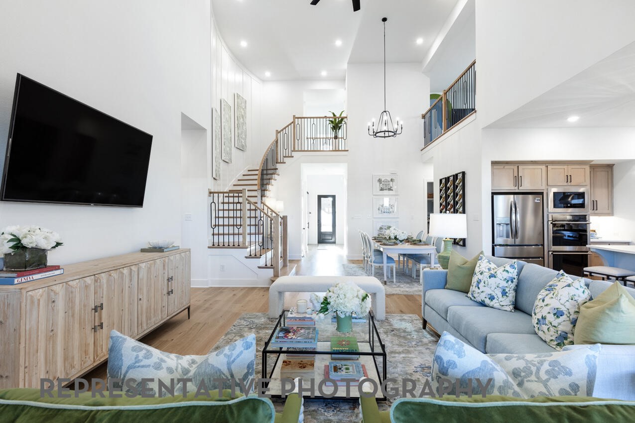 Representative Photo- Grand family room featuring soaring ceilings, a dramatic staircase, and an open-concept layout. Representative Photo- Grand family room featuring soaring ceilings, a dramatic staircase, and an open-concept layout.