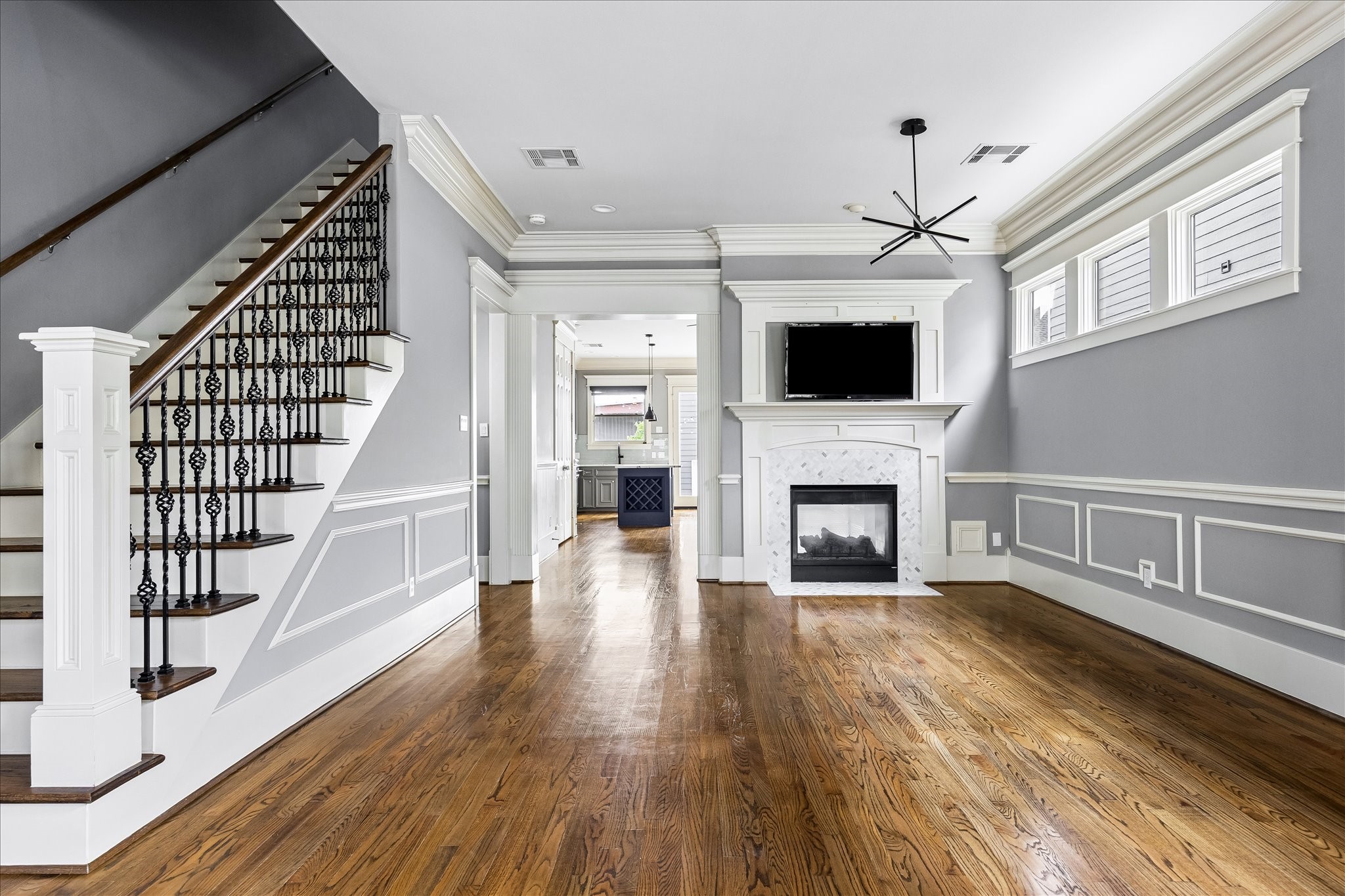 An elegant staircase with ornamental iron balusters, rich hardwood floors, and a beautifully framed fireplace lend timeless character to the living room. An elegant staircase with ornamental iron balusters, rich hardwood floors, and a beautifully framed fireplace lend timeless character to the living room.