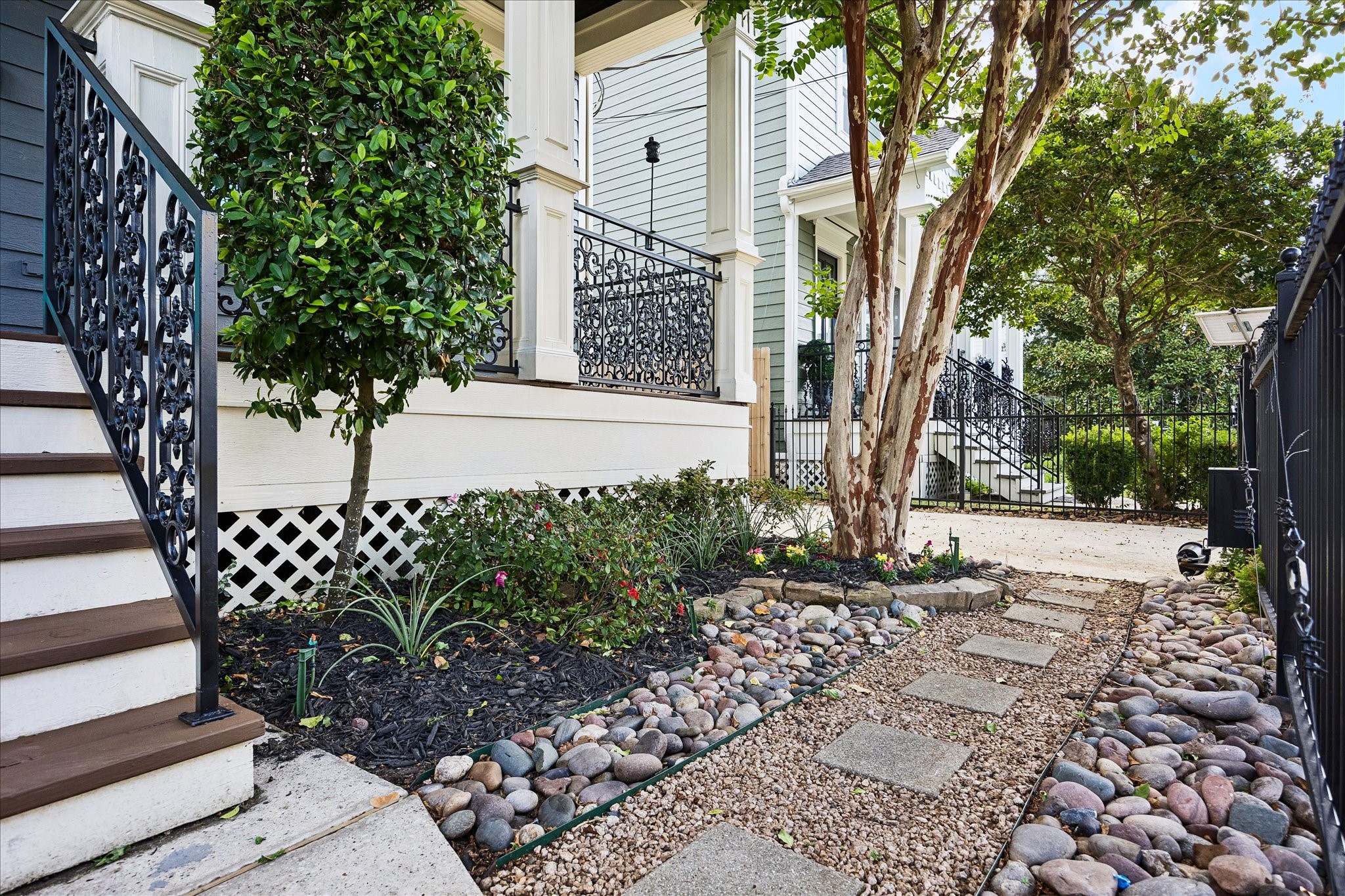 A charming stepping-stone pathway winds through thoughtfully landscaped garden beds beneath the shade of mature trees.
