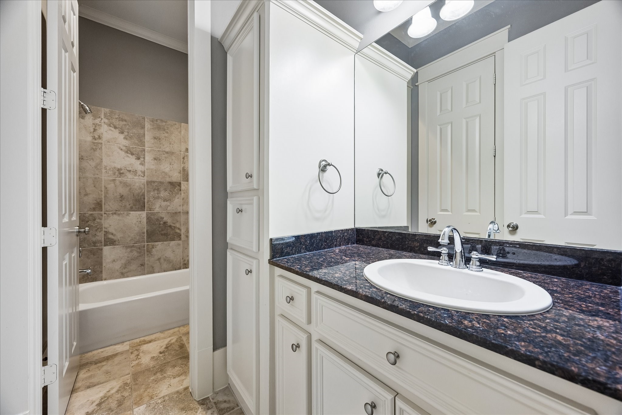 The shared Jack-and-Jill bath features a granite-topped vanity, generous cabinetry, and a tub-shower combination.